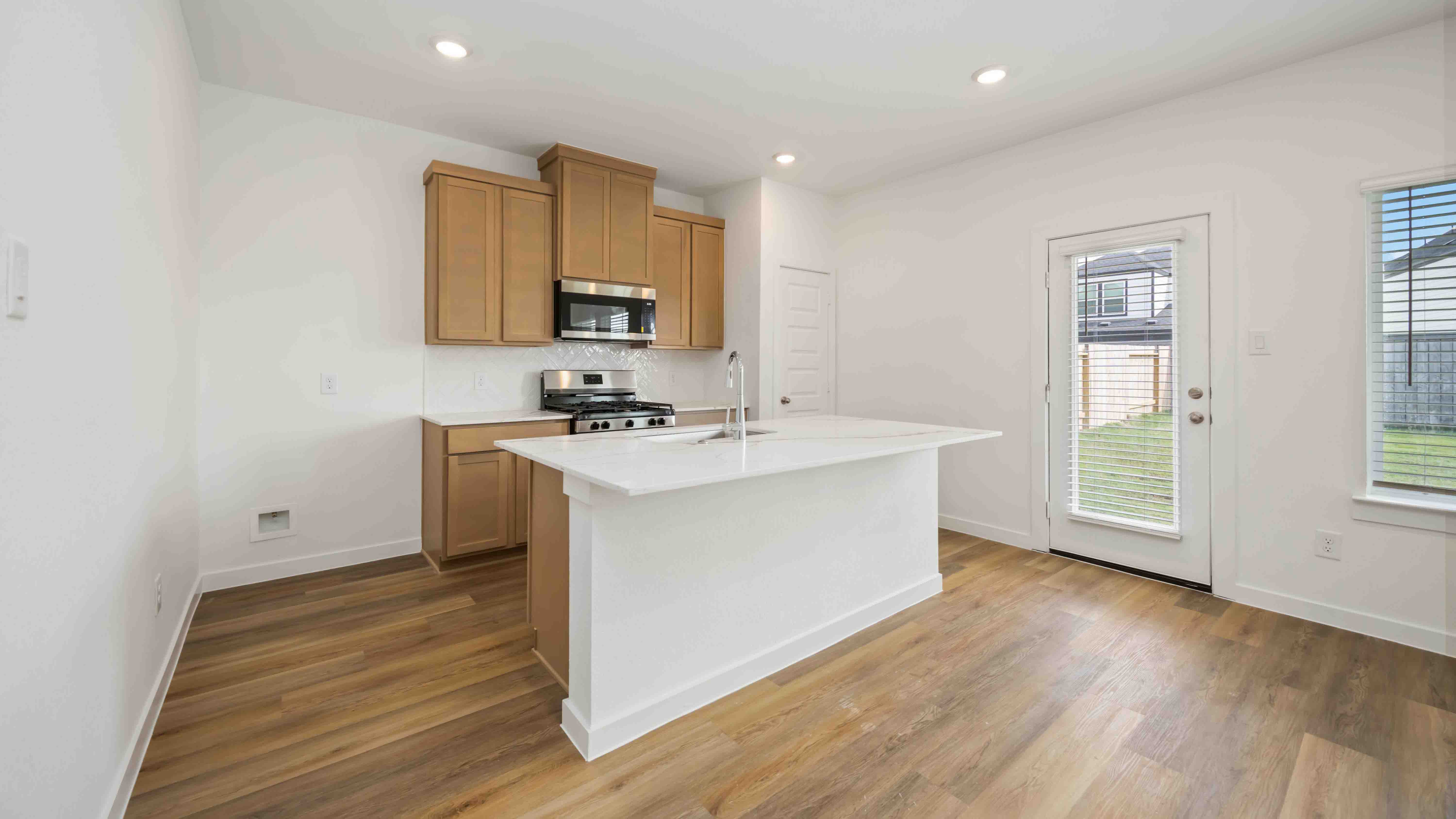 beautiful new kitchen with quartz counter tops, wood cabinets, and herringbone backsplash