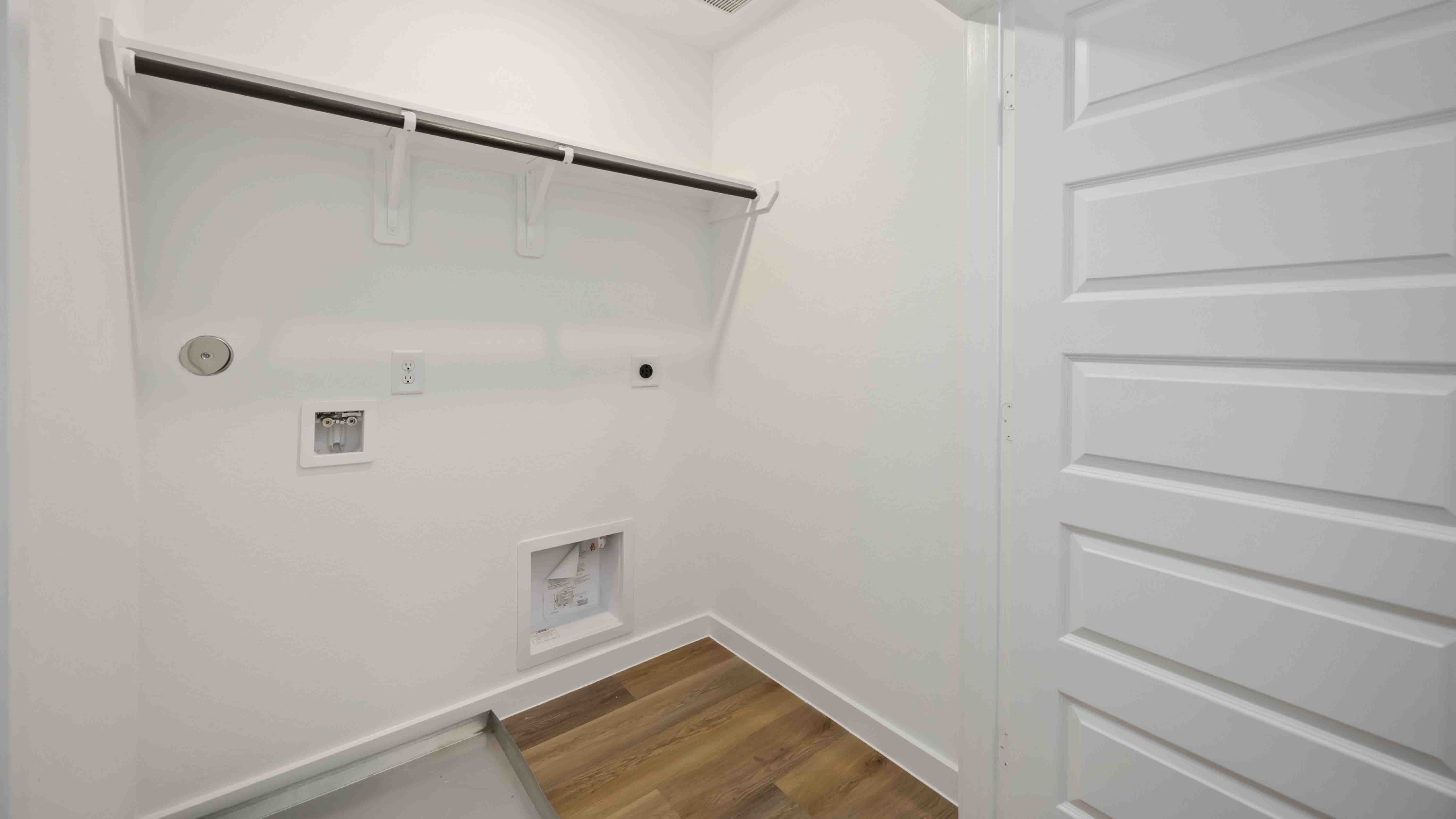 laundry room area with an open shelf and rod for additional storage and hanging clothes