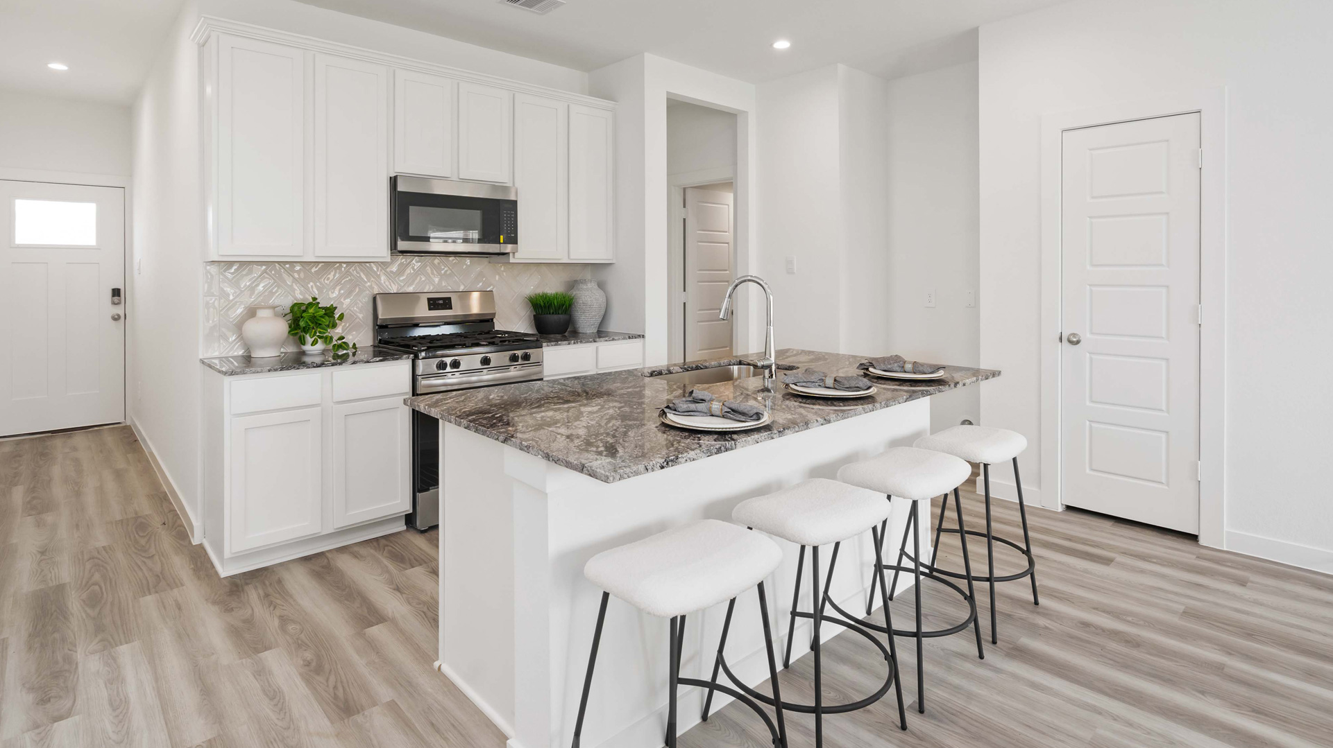 beautiful new kitchen with granite counters, light cabinets, and herringbone backsplash