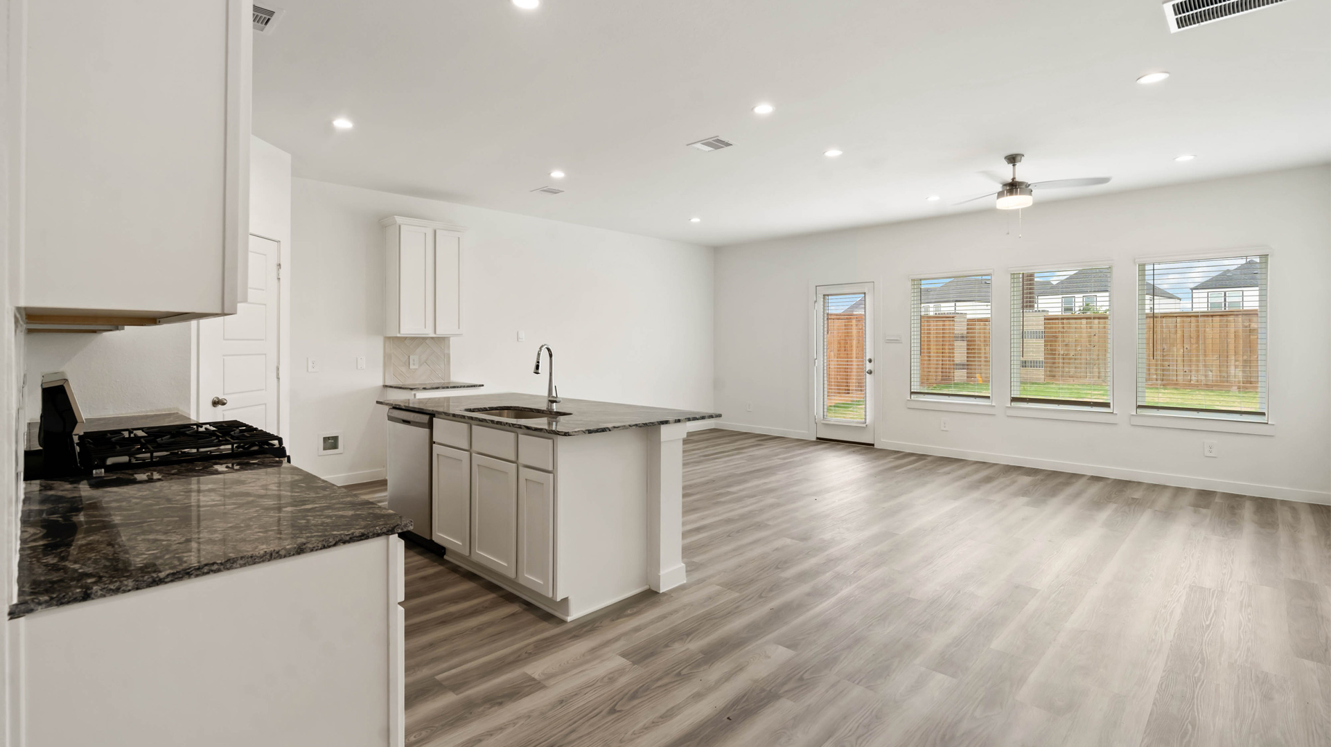 beautiful new kitchen with granite counters, light cabinets, and herringbone backsplash