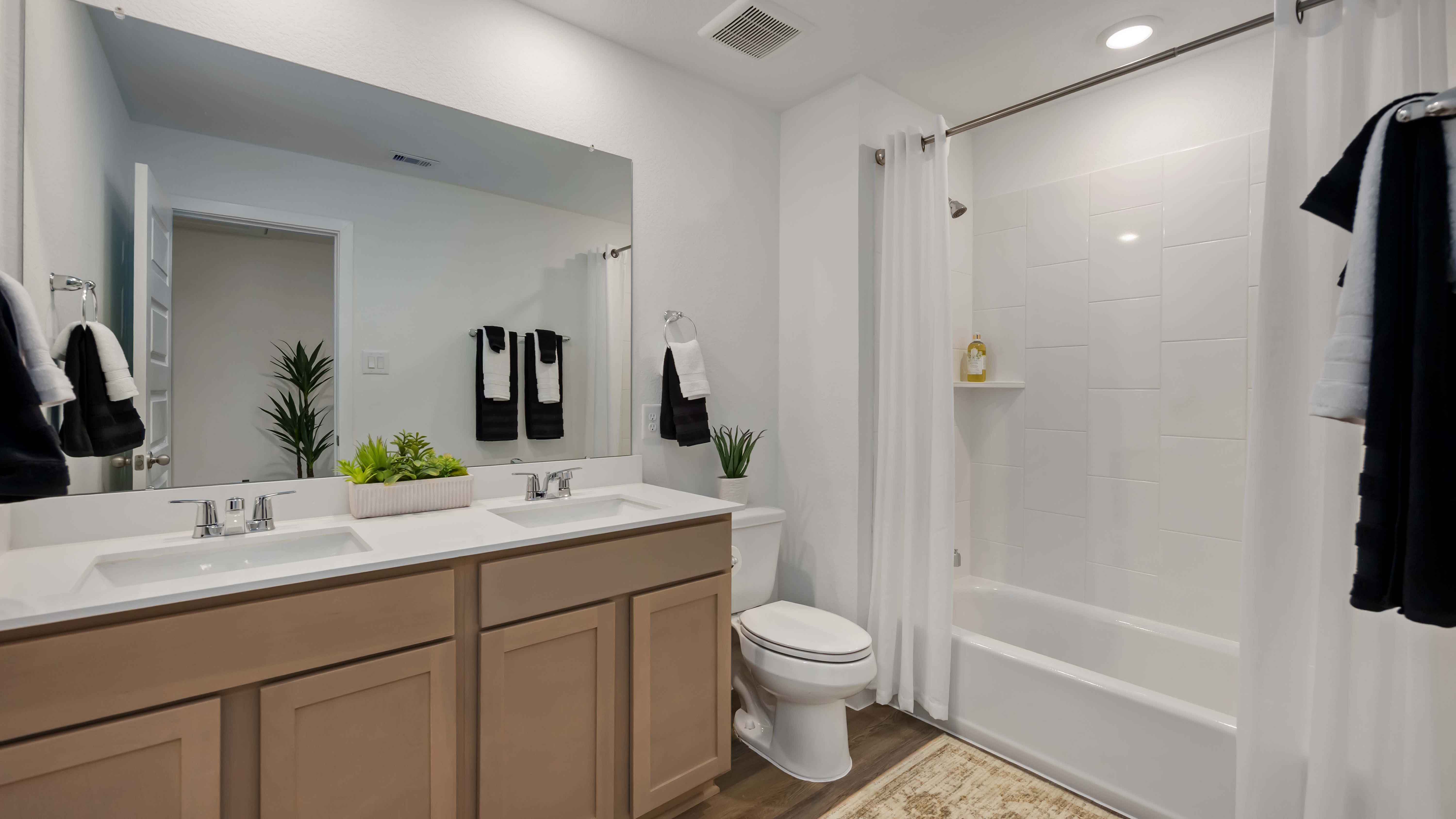 a spacious secondary bathroom with a two sink vanity and standing tub