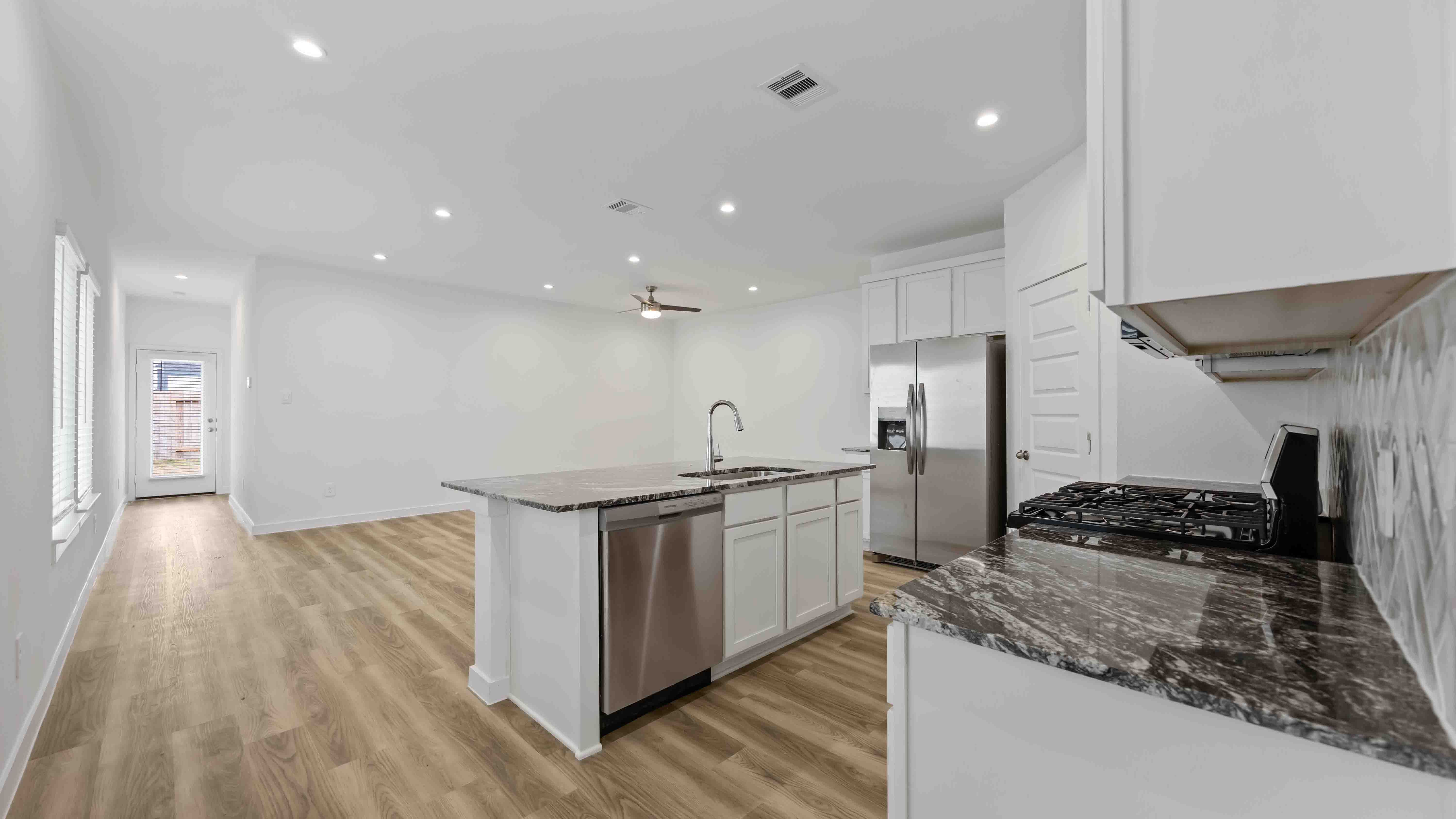 beautiful new kitchen with granite counters, light cabinets, and herringbone backsplash