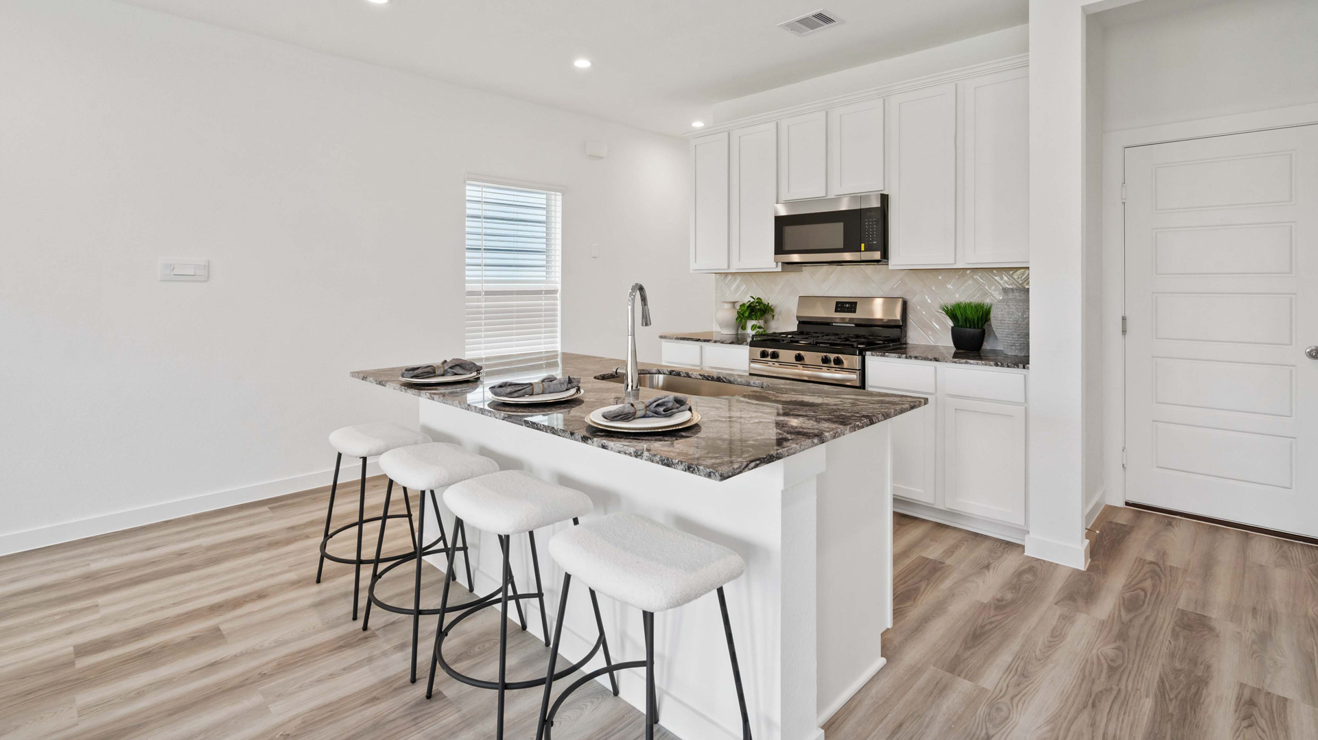 beautiful new kitchen with granite counters, light cabinets, and herringbone backsplash
