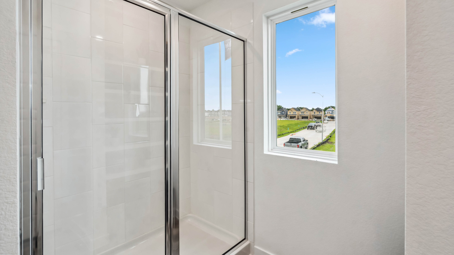 the walk-in shower has a glass enclosure and tiled walls in the primary bathroom