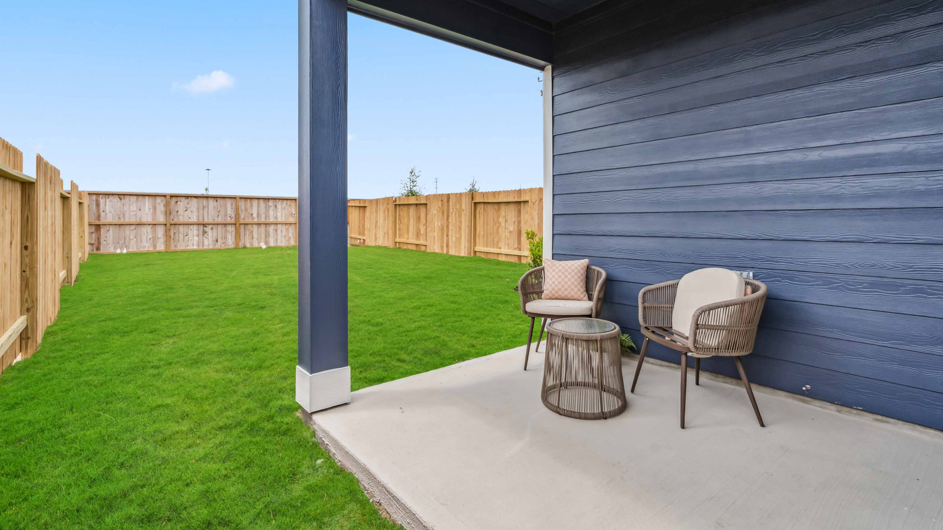 the covered patio overlooks a spacious backyard that's fenced in for privacy