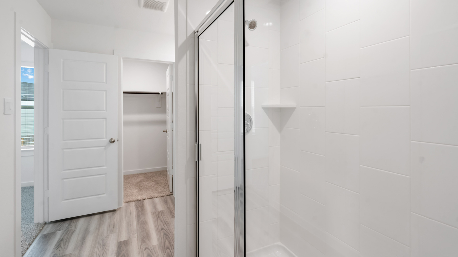 walk-in shower has a glass enclosure and tiled walls