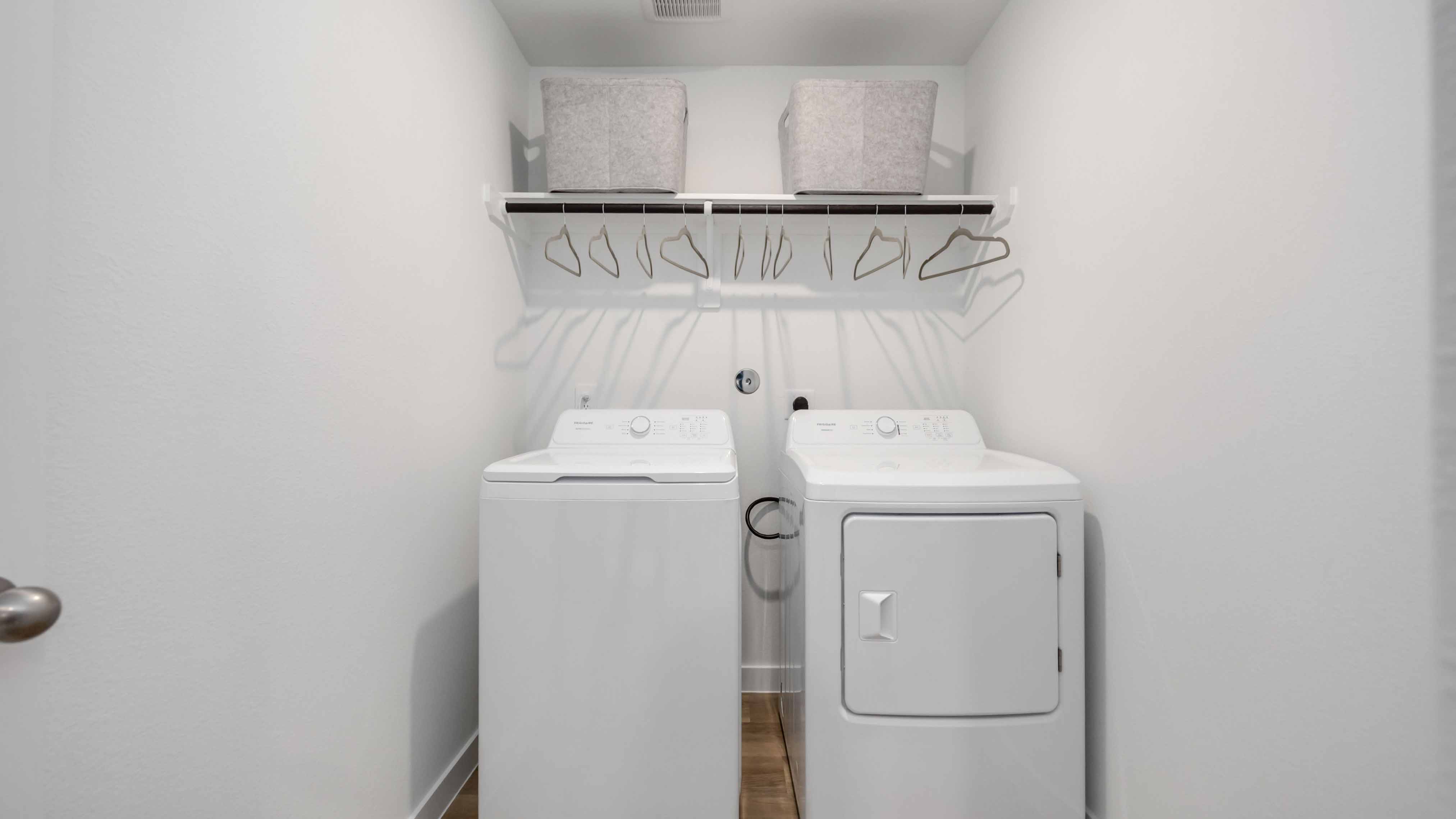 laundry room area with an open shelf and rod for additional storage and hanging clothes