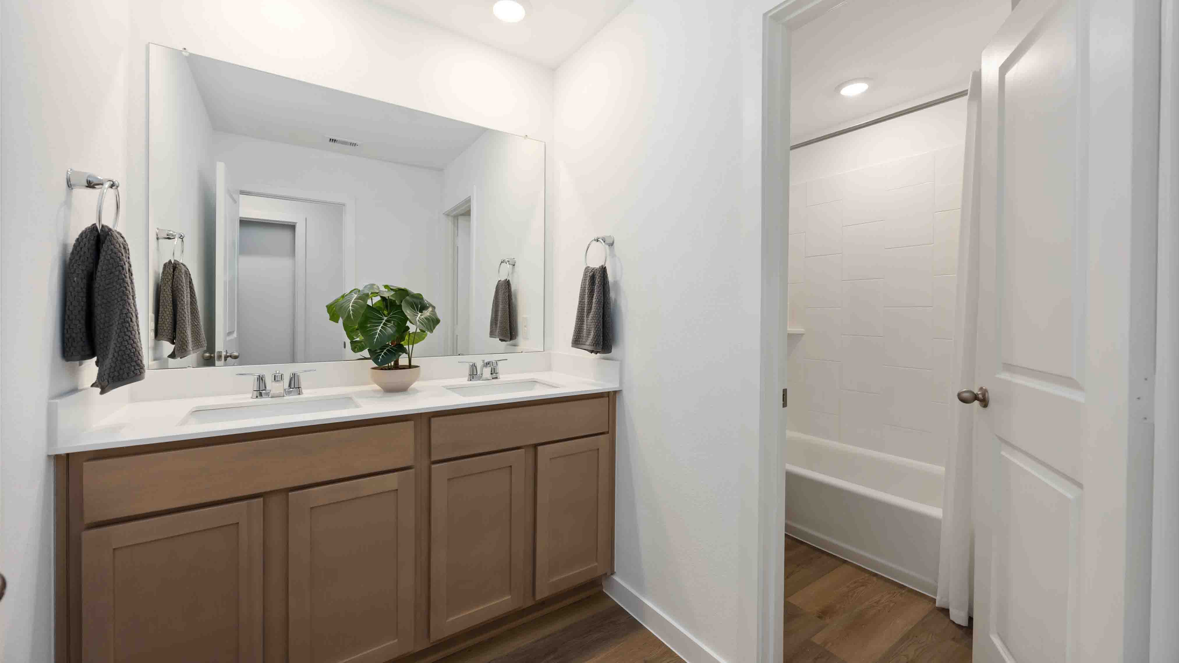 a spacious secondary bathroom with a two sink vanity and standing tub