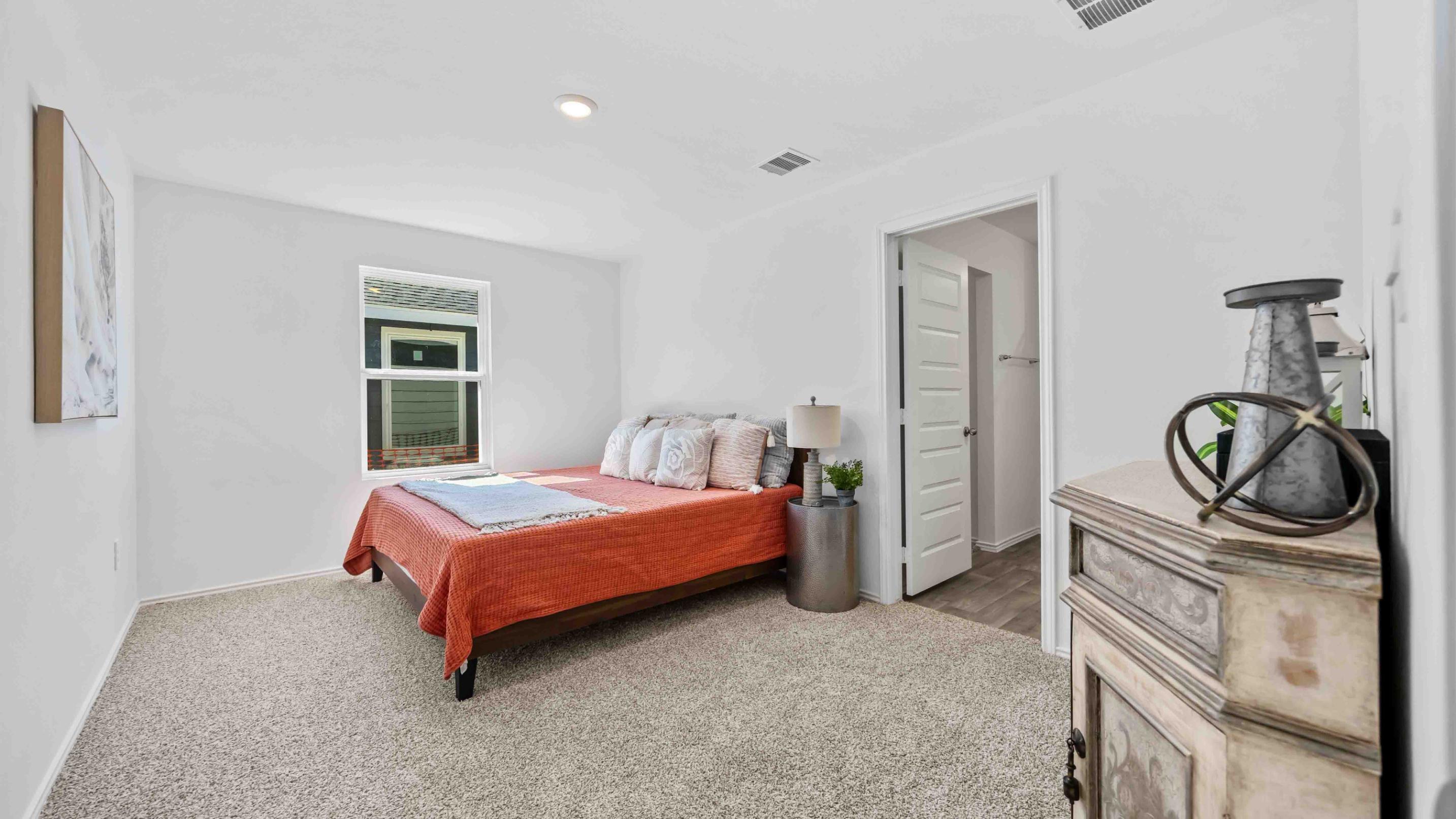 Primary bedroom with ceiling fan, plush carpeting, and a large walk-in closet.