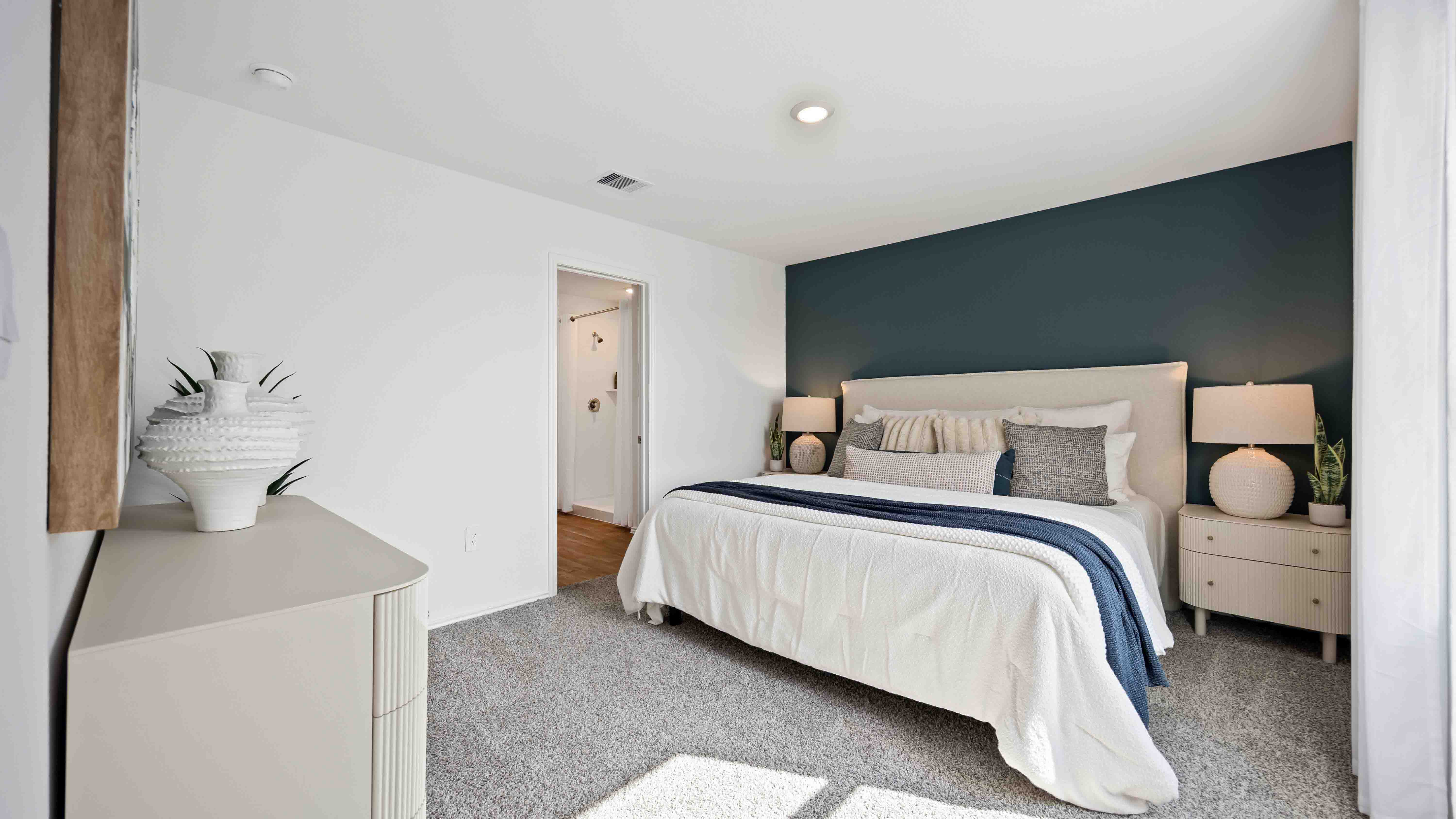 a spacious primary suite comfortably fits a queen size bed and additional bedroom furniture