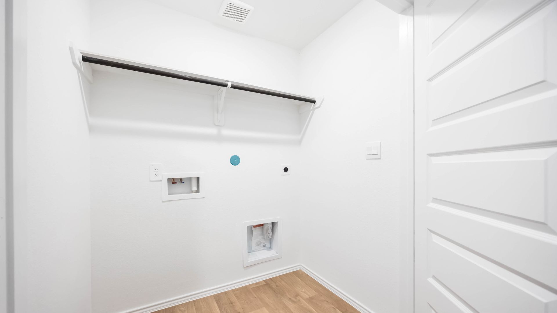 laundry room area with an open shelf and rod for additional storage and hanging clothes
