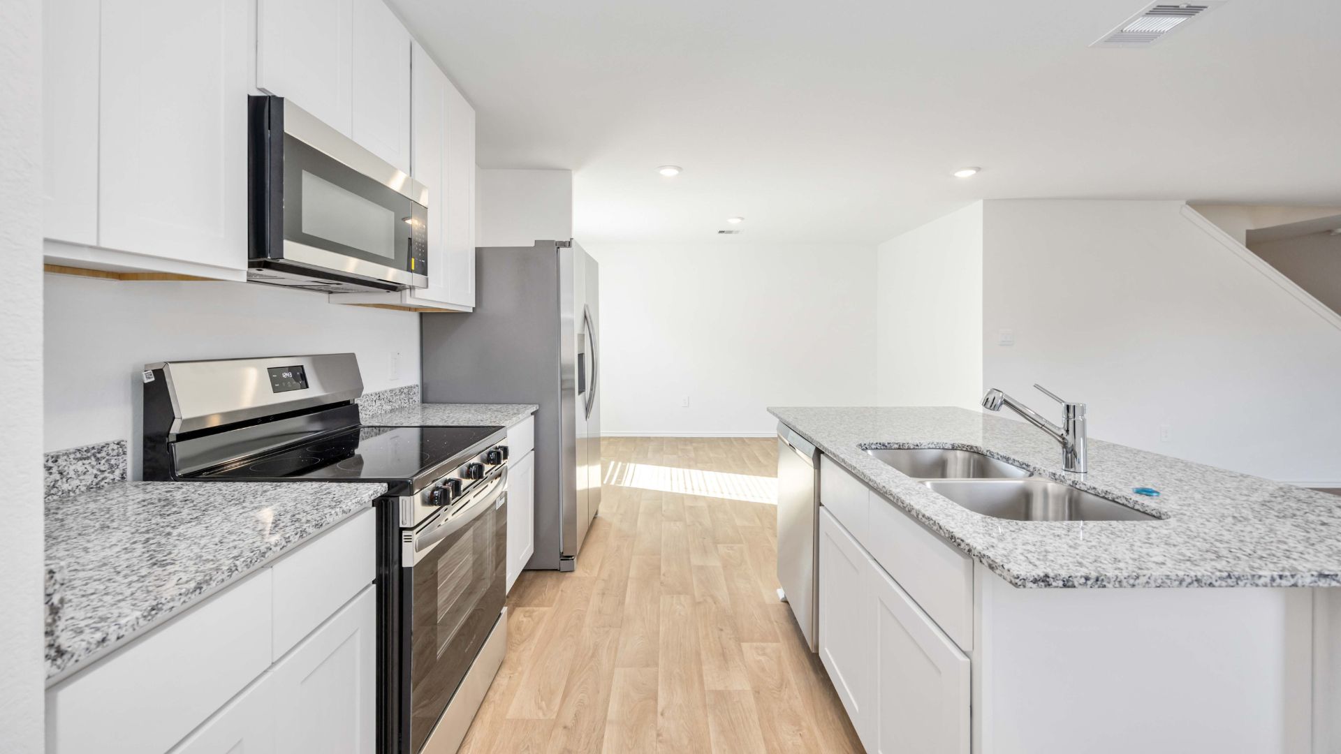 Bright and spacious kitchen with granite countertops, stainless steel appliances, and an island with bar seating.