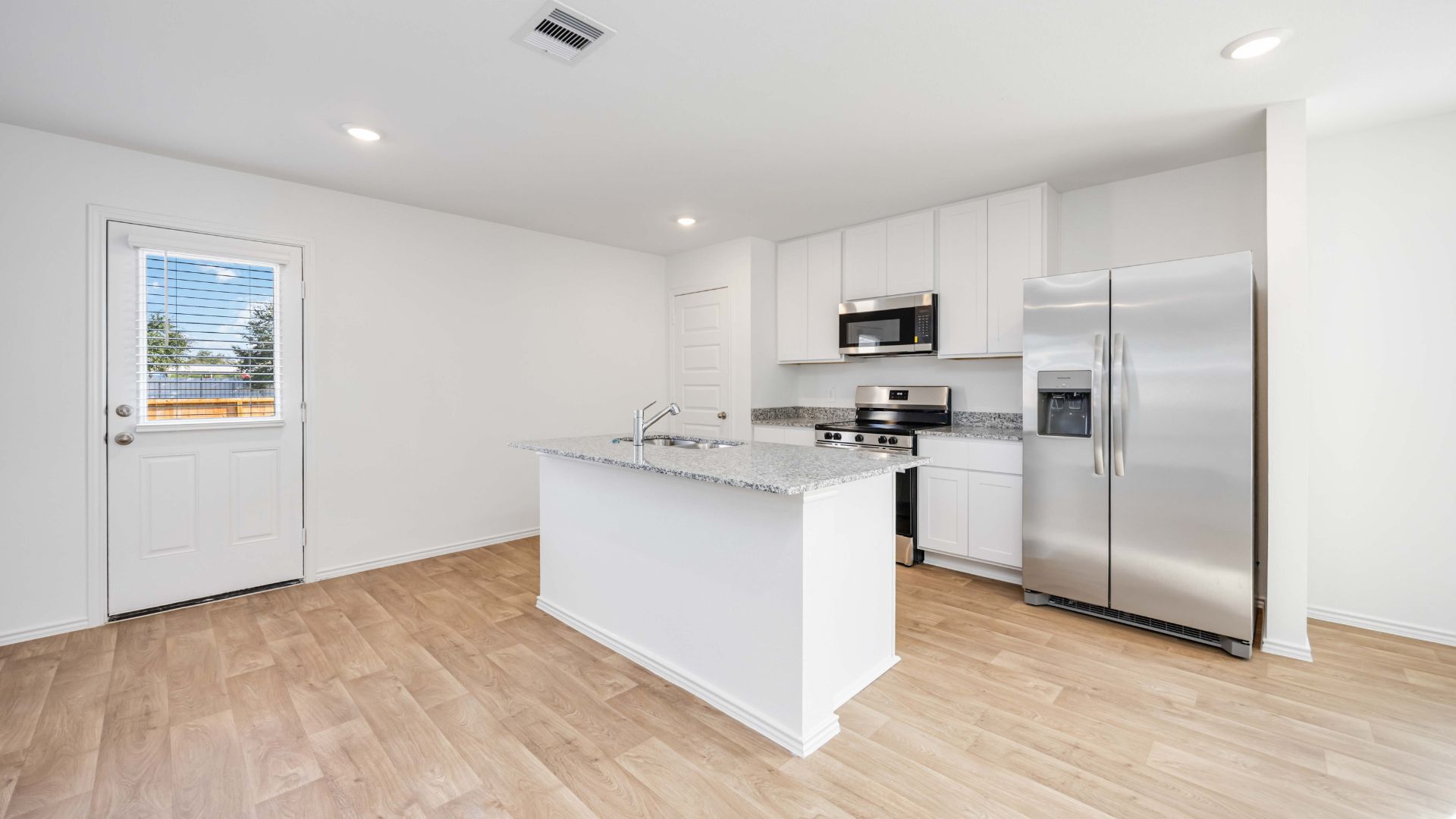 Contemporary kitchen adorned with white cabinets seamlessly integrated into an open dining area layout.