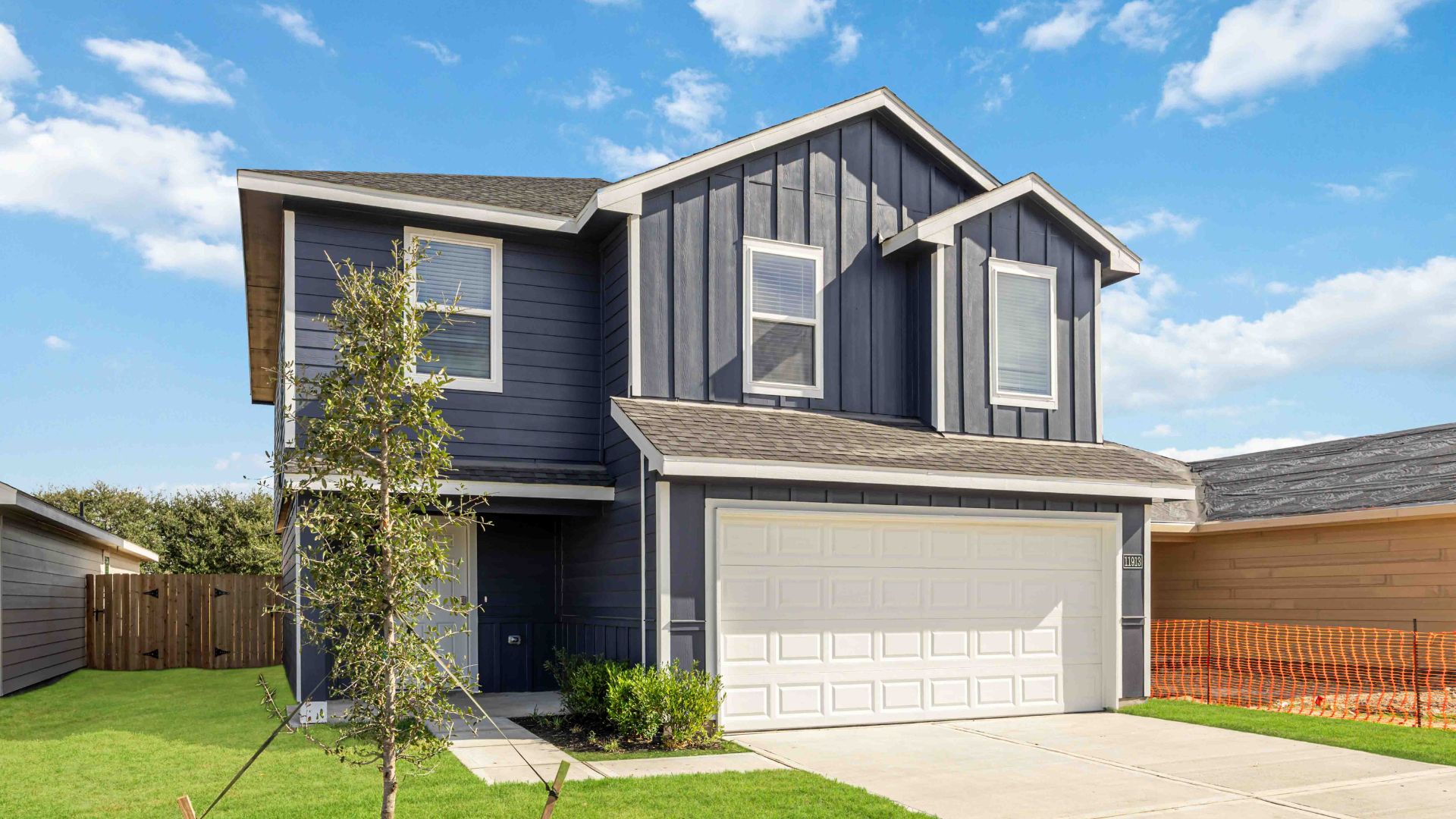 Newly built two-story home with modern architecture, a double garage, and landscaped front yard.