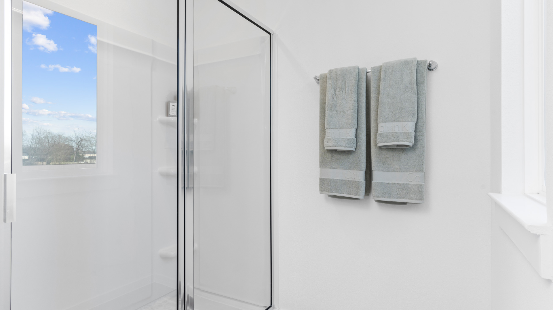 a walk-in shower with tiled walls and a glass enclosure awaits you in the primary bathroom