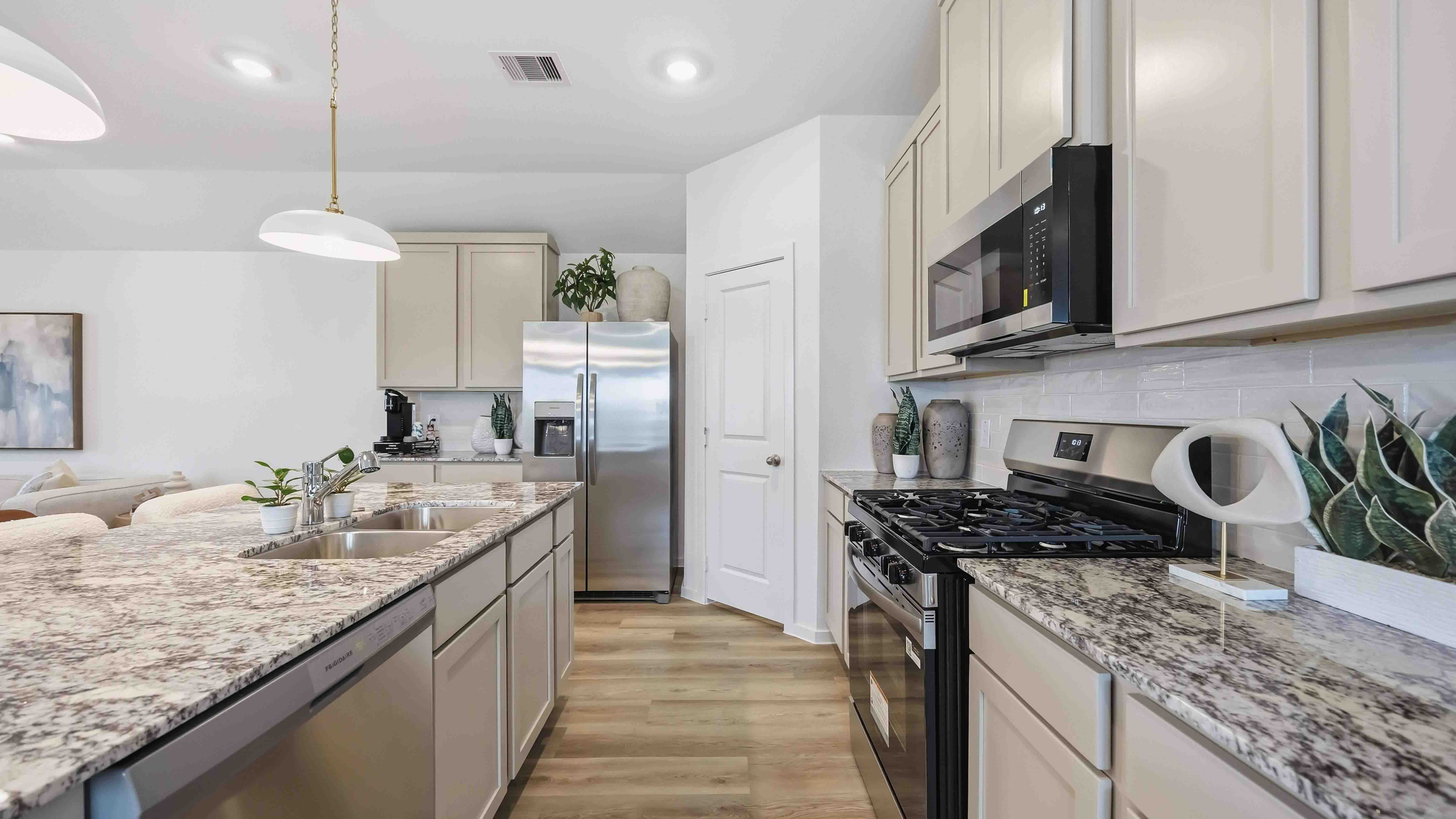 beautiful new kitchen with granite counter tops, light grey cabinets, and herringbone backsplash