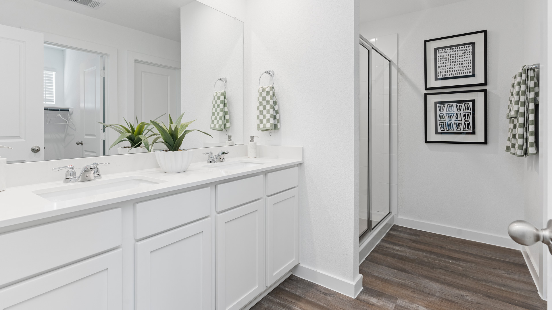 the en-suite primary bathroom has a quartz double vanity, a standing shower, and spacious walk-in closet