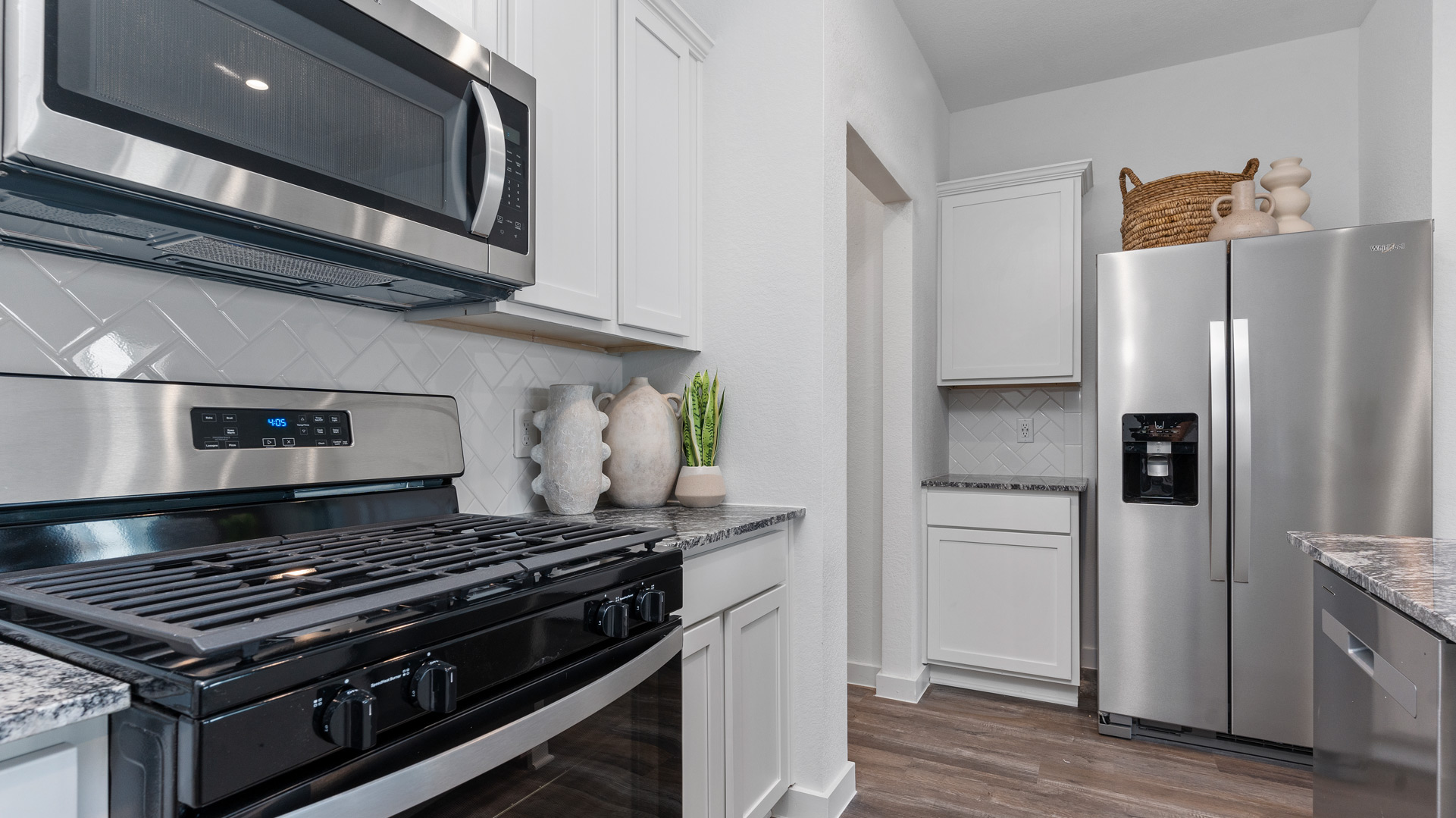 beautiful new kitchen with quartz counters, navy cabinets, and herringbone backsplash
