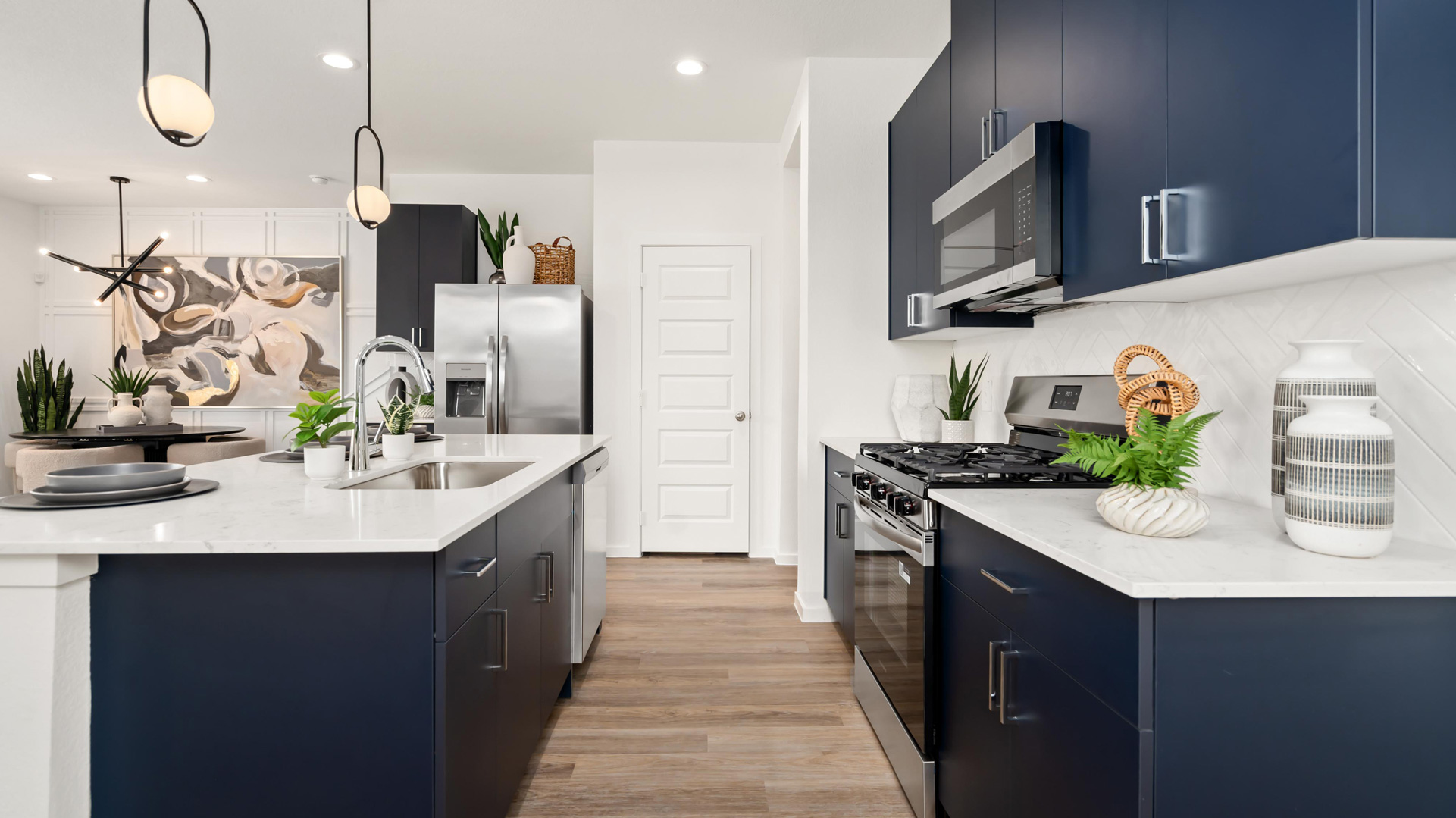 beautiful new kitchen with quartz counters, navy cabinets, and herringbone backsplash