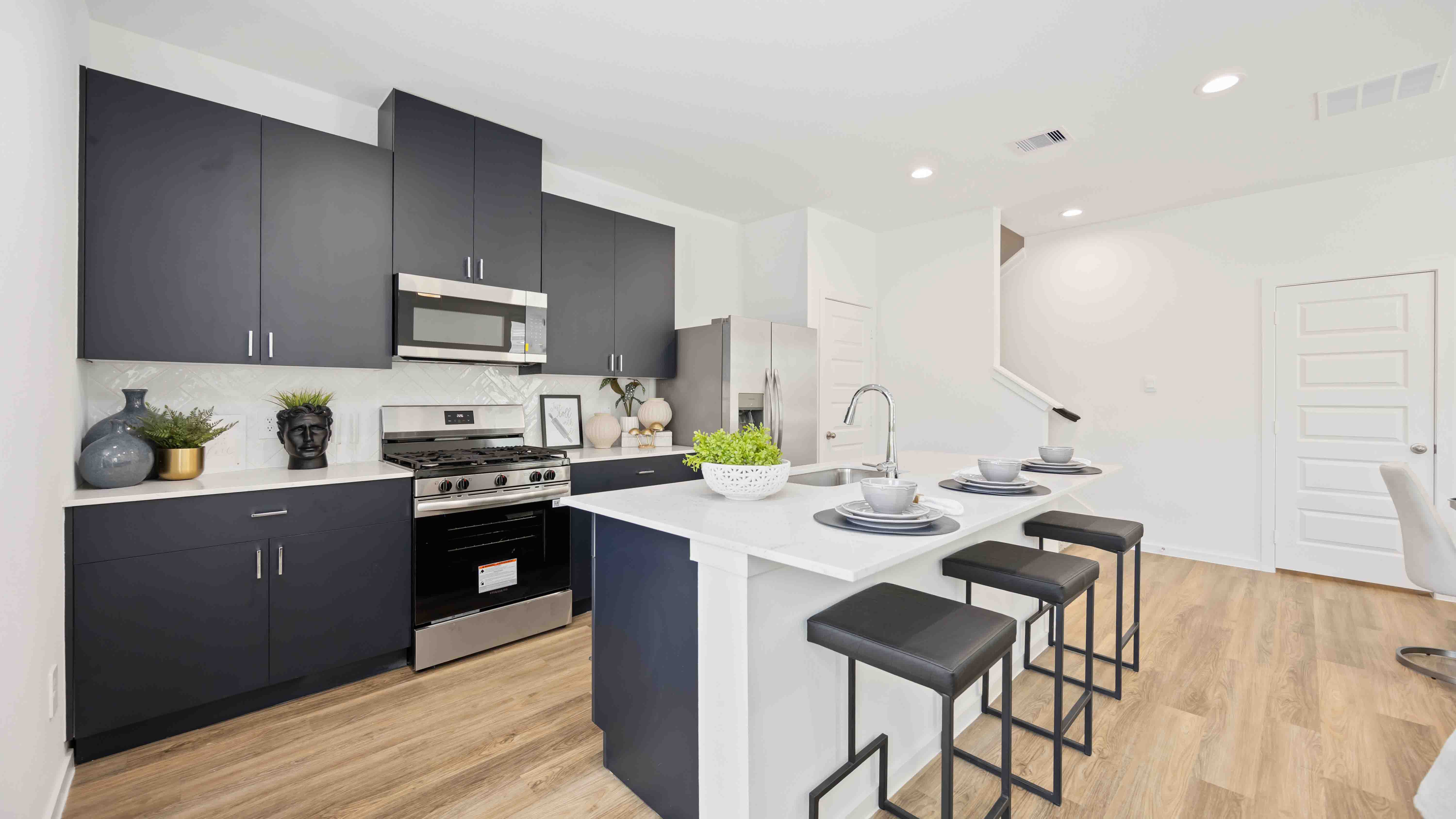 beautiful new kitchen with quartz counters, navy cabinets, and herringbone backsplash