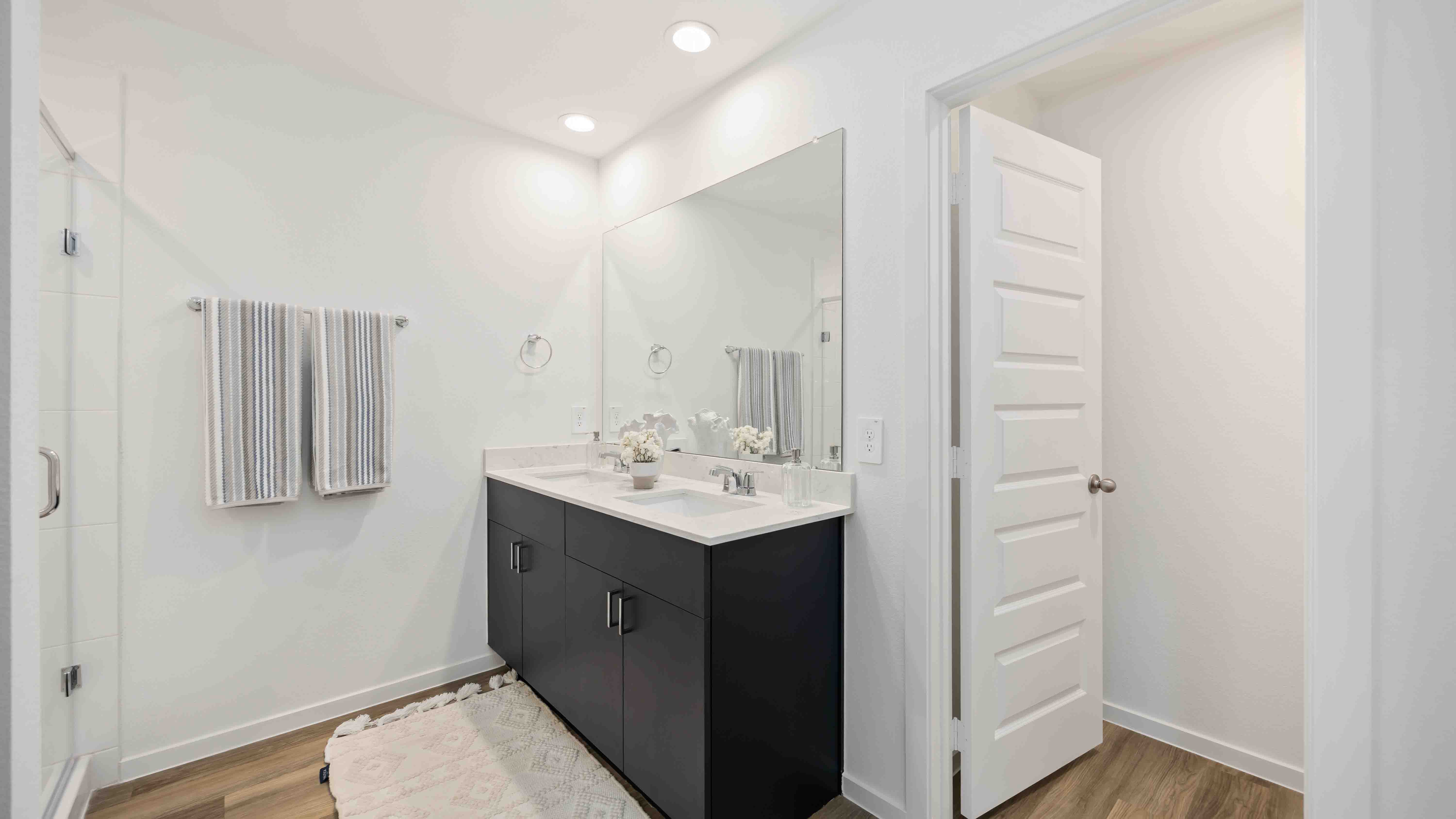 the en-suite primary bathroom has a quartz double vanity, a standing shower, and spacious walk-in closet