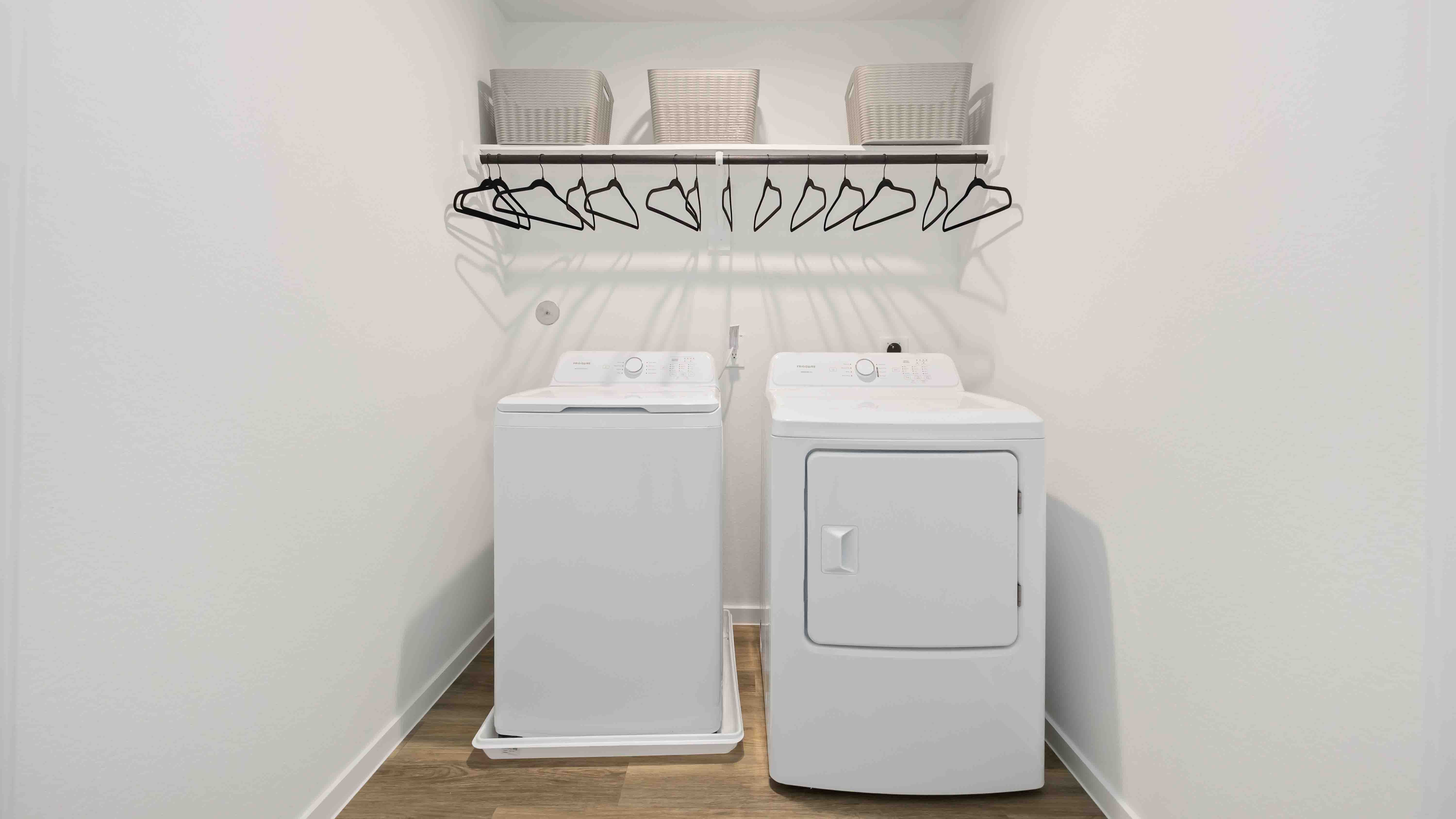 laundry room area with an open shelf and rod for additional storage and hanging clothes