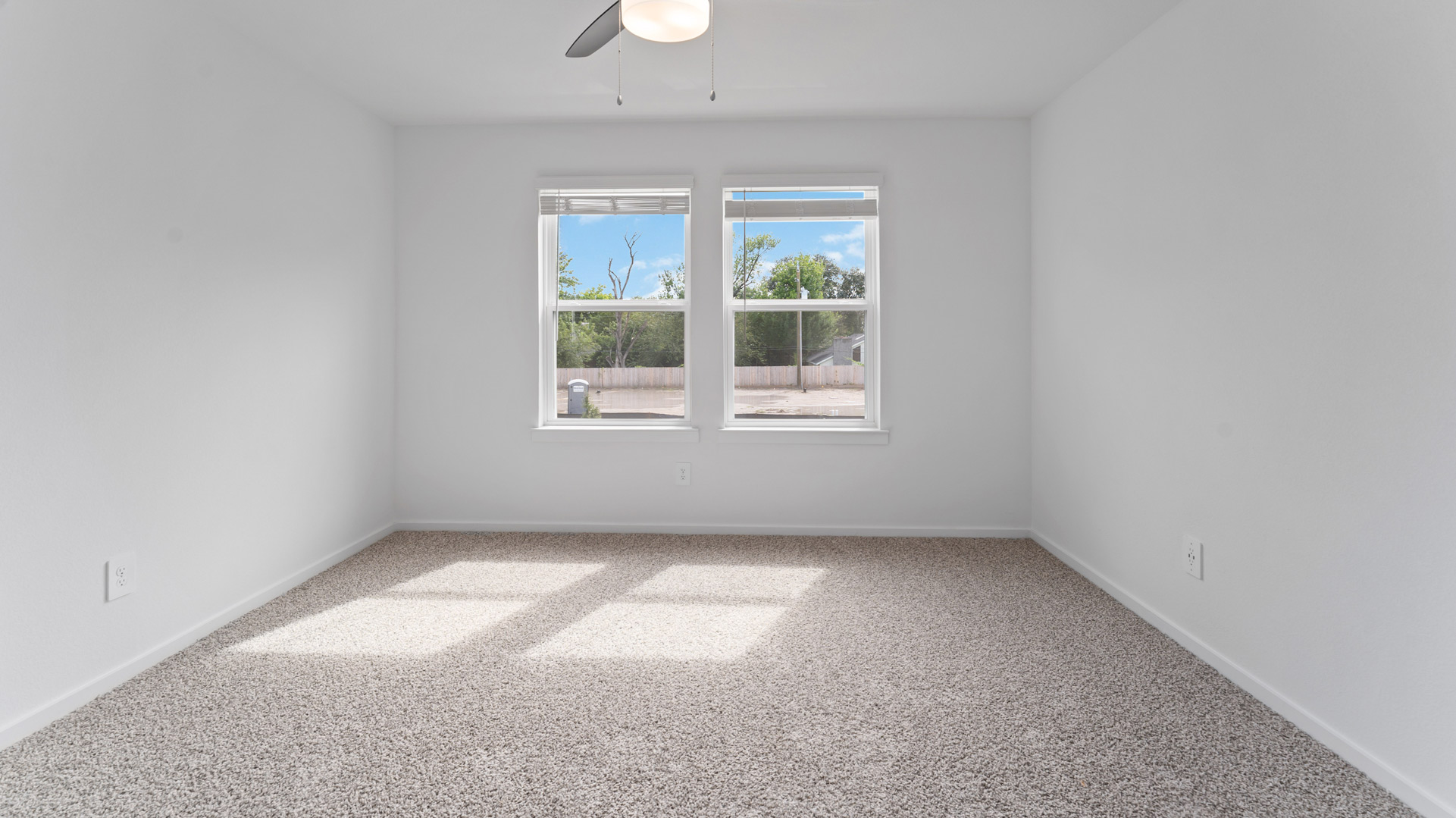 the primary bedroom has light neutral walls and carpet flooring