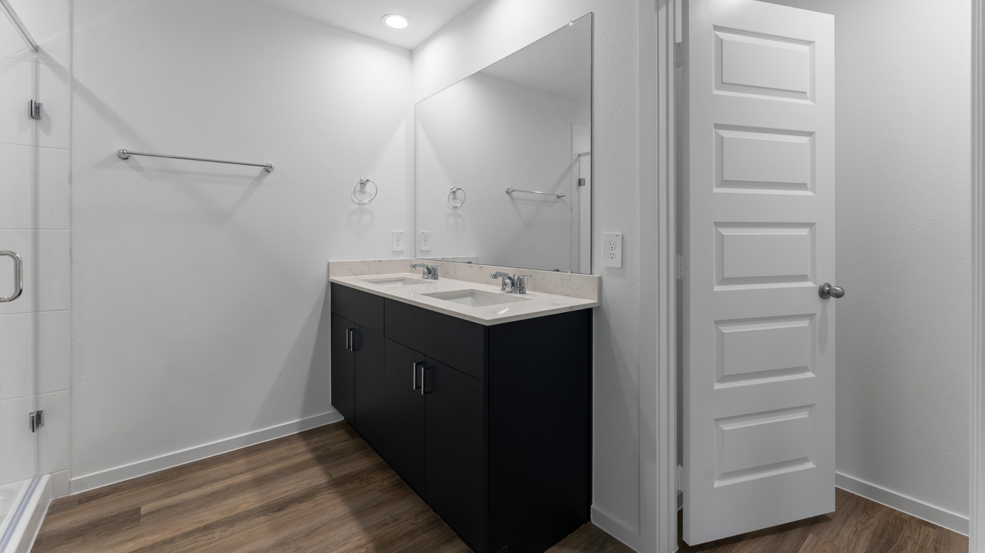 an en-suite primary bathroom has a large mirror over a double-vanity and a walk-in shower