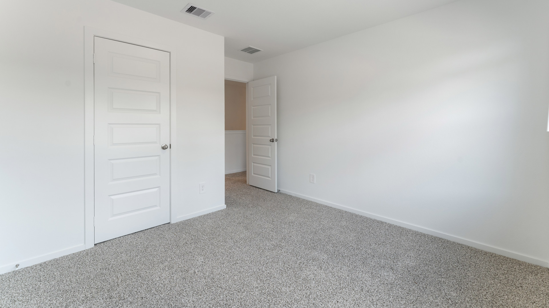 the second bedroom has light neutral walls and carpet flooring