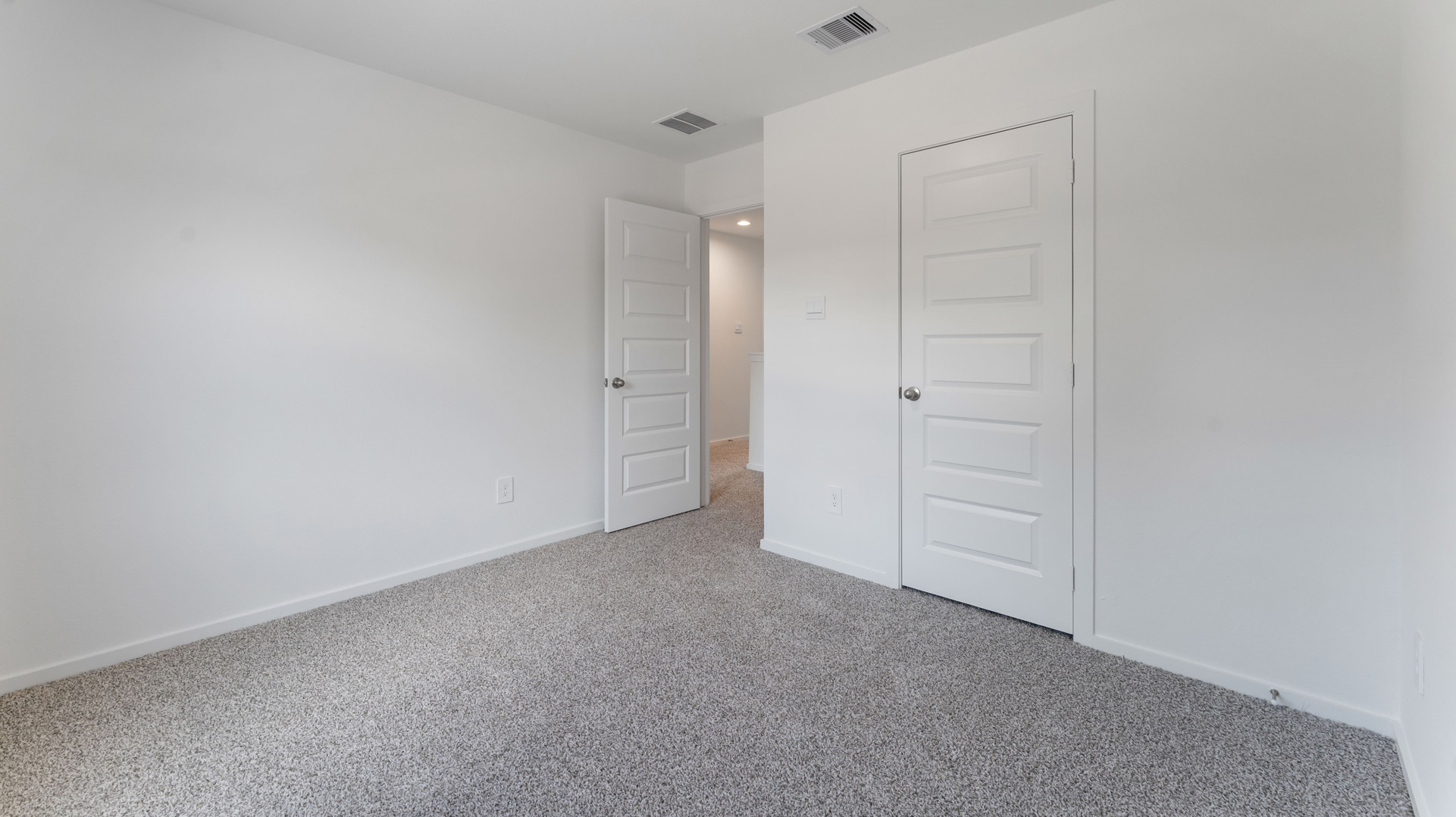 the third bedroom, located upstairs, has light neutral walls and carpet flooring