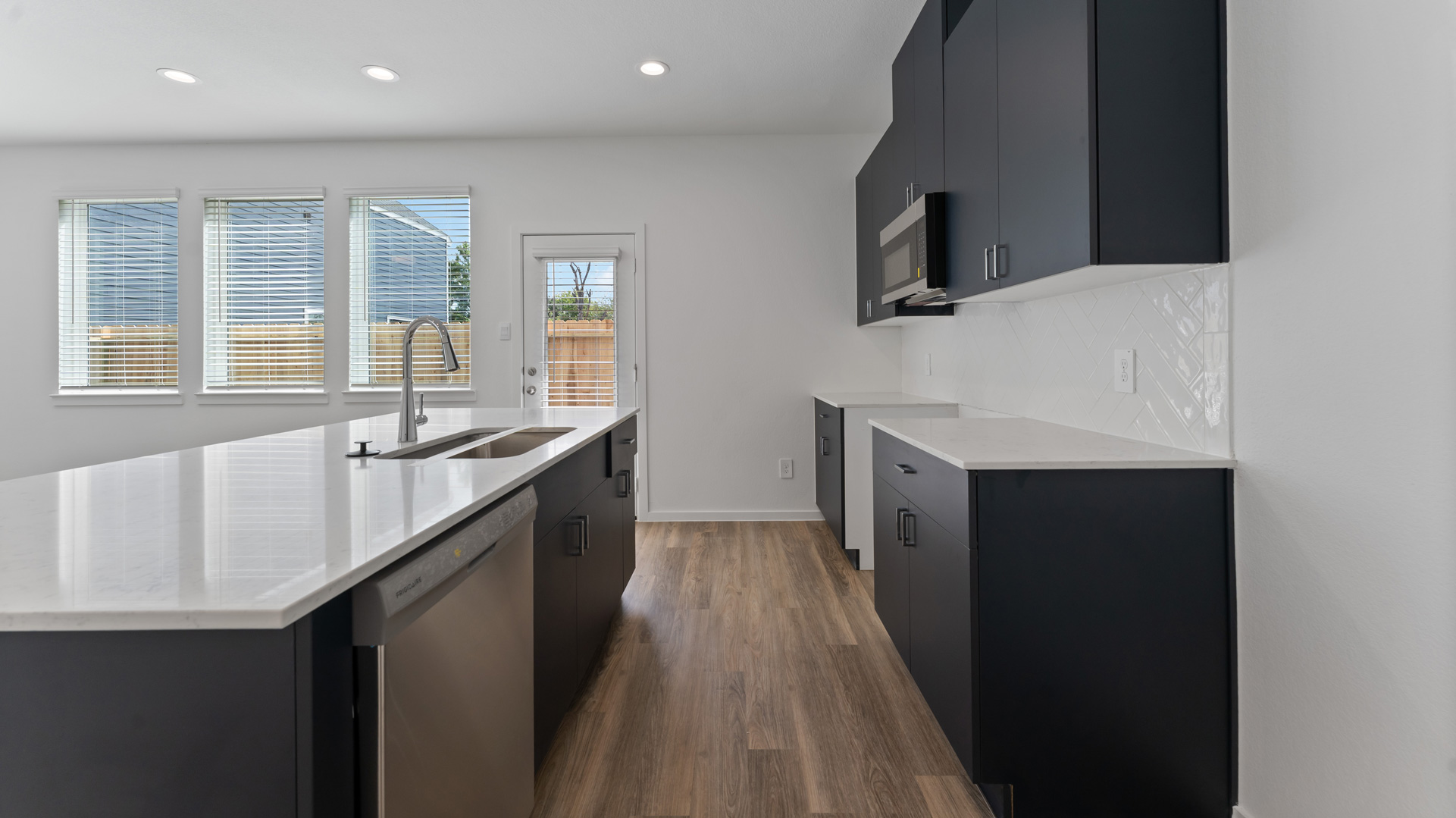 new kitchen with navy cabinets, white quartz countertops, and white tile backsplash