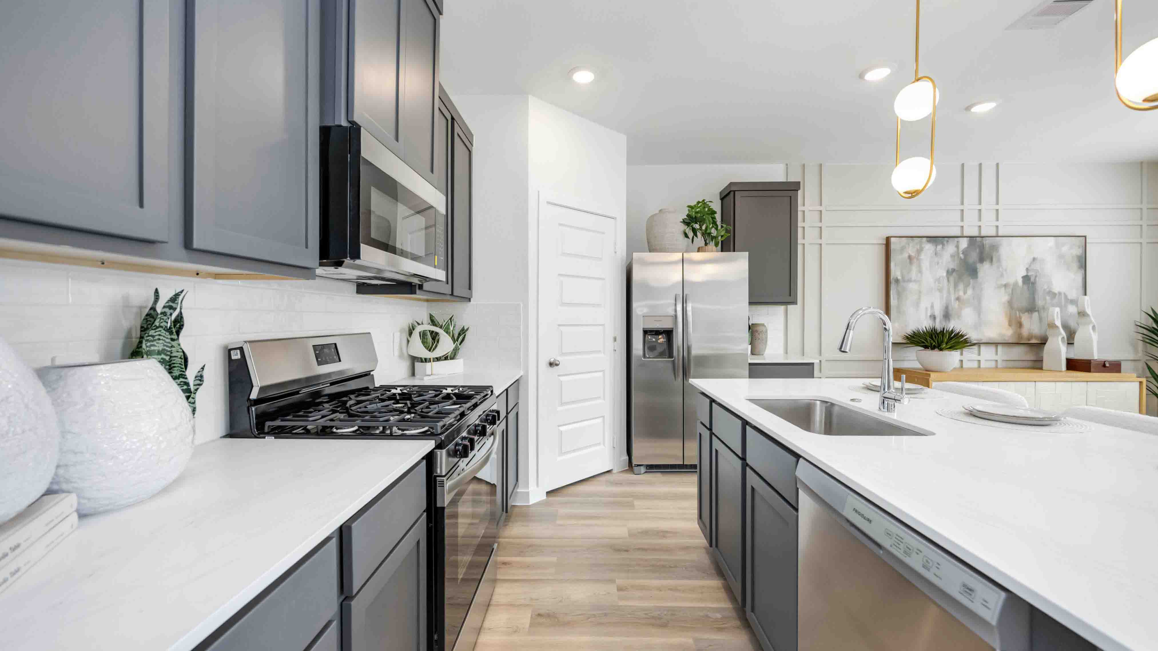 beautiful new kitchen with quartz counters, dark grey cabinets, and herringbone backsplash