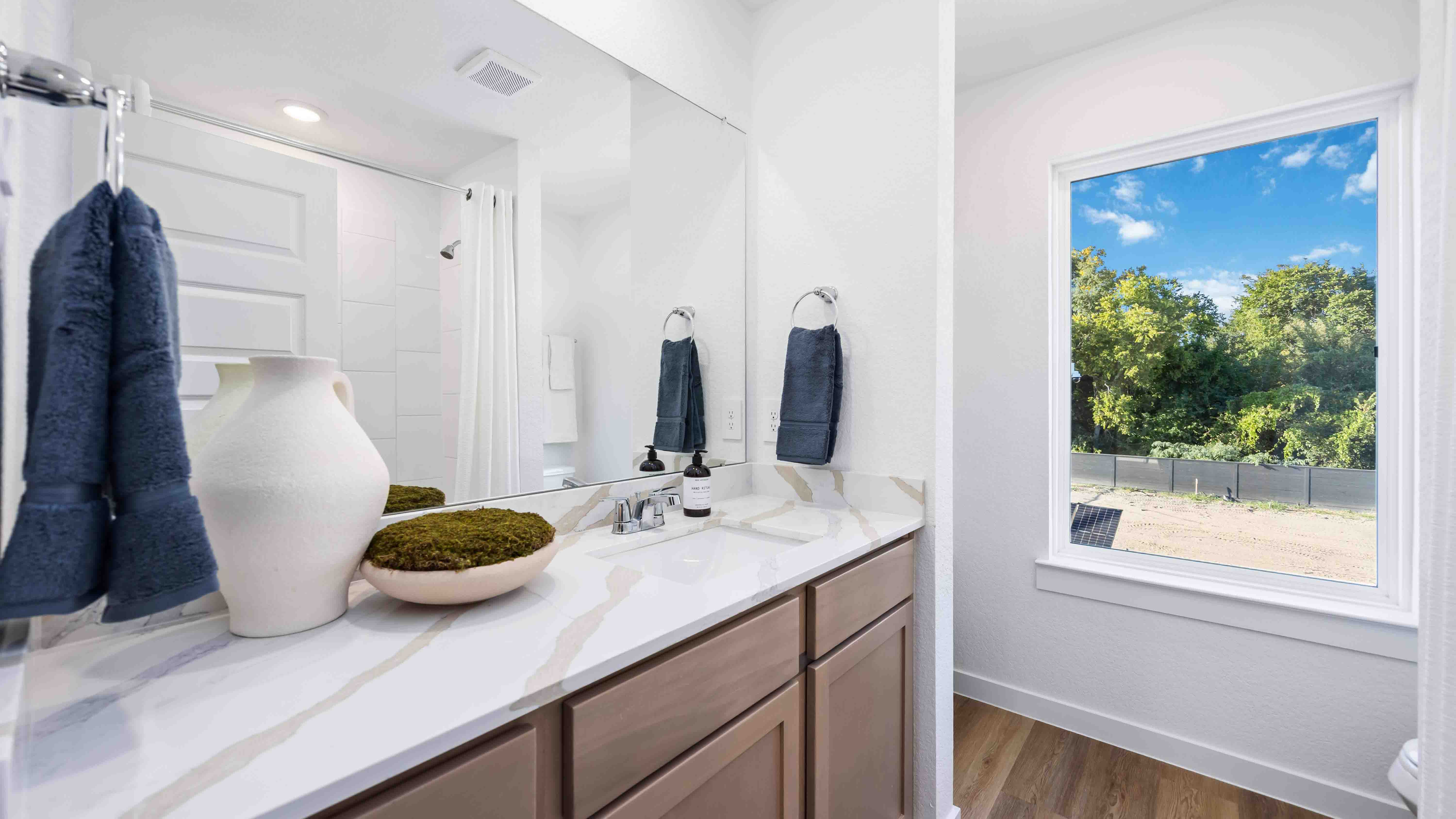 secondary bathroom with the same quartz countertops and wood-colored cabinets with a standing tub