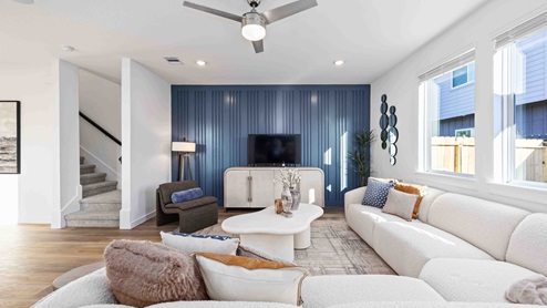 living room with ceiling fan and natural lighting from windows to backyard