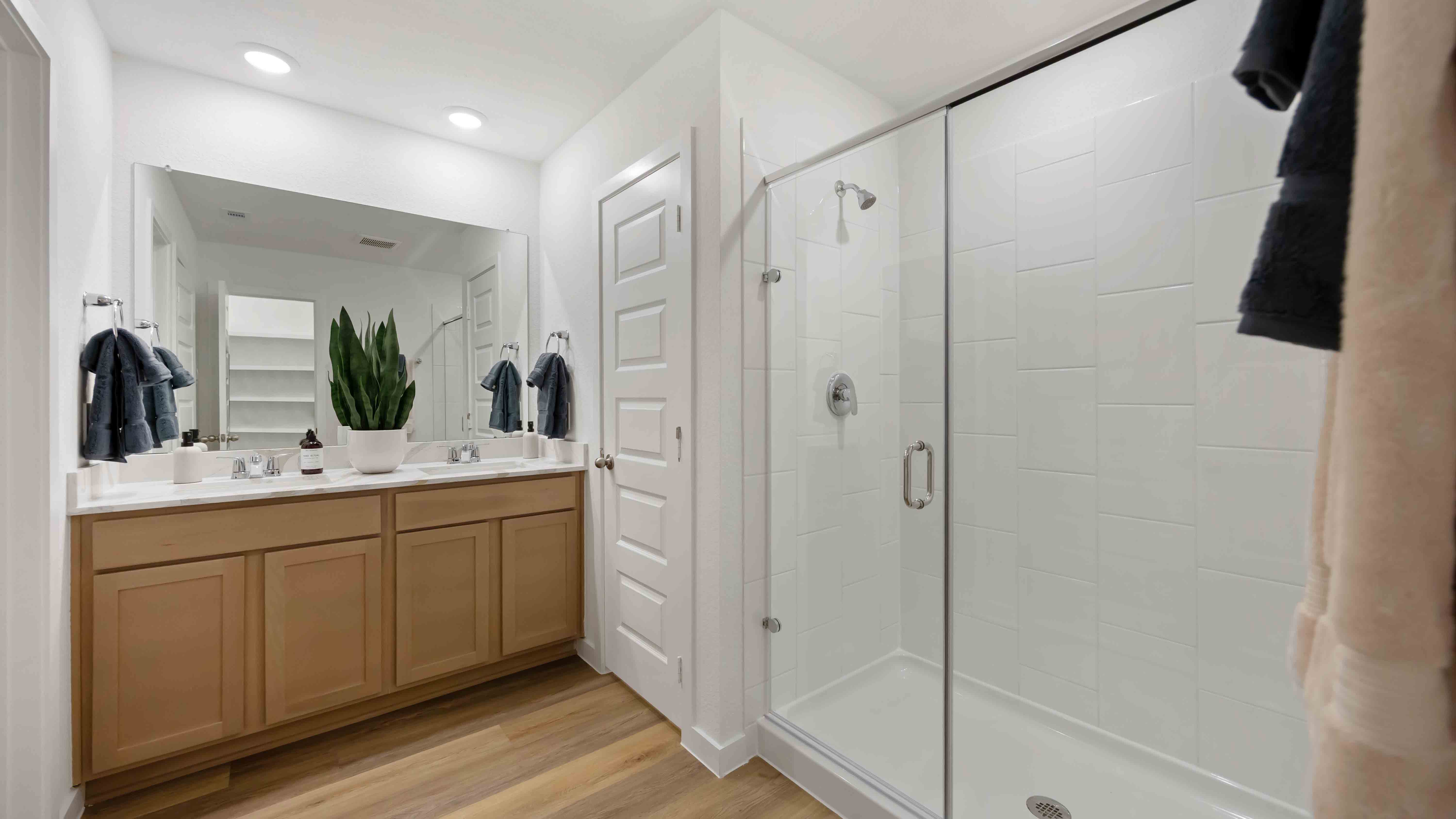 primary bathroom with a standing semi-frameless shower and a double vanity sink with the same quartz countertop as the kitchen