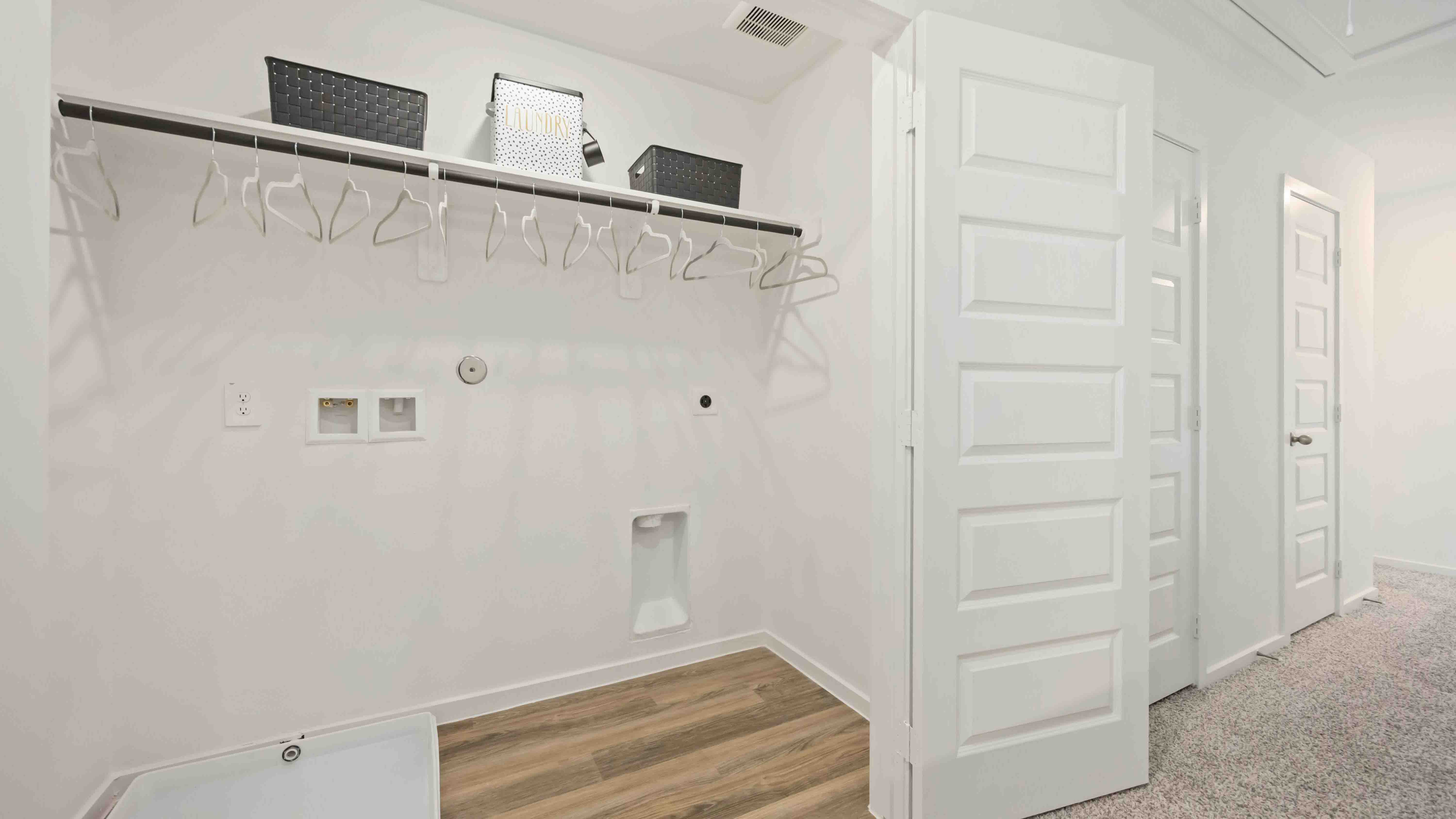laundry room area with an open shelf and rod for additional storage and hanging clothes