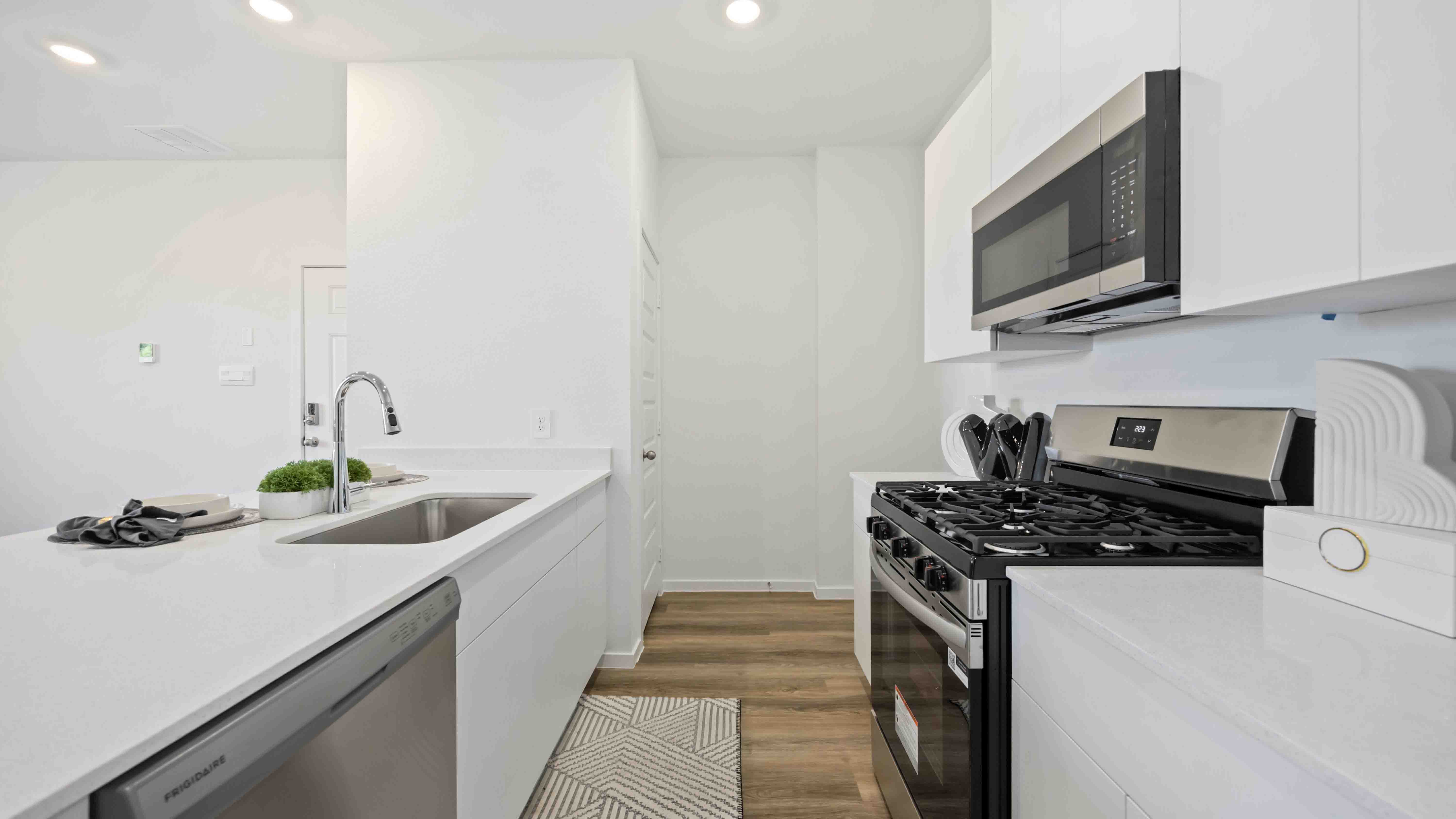 beautiful new kitchen with quartz counters, white cabinets, and stainless steel appliances