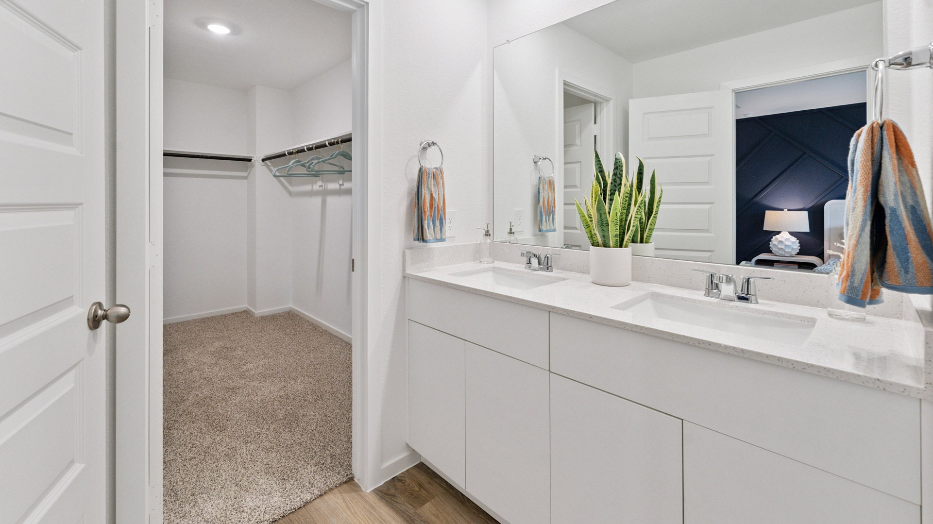 an en-suite primary bathroom has a large mirror over the doubel vanity