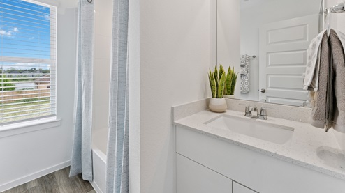 a second full bathroom is located upstairs and has a mirror above the vanity and a shower/tub combo