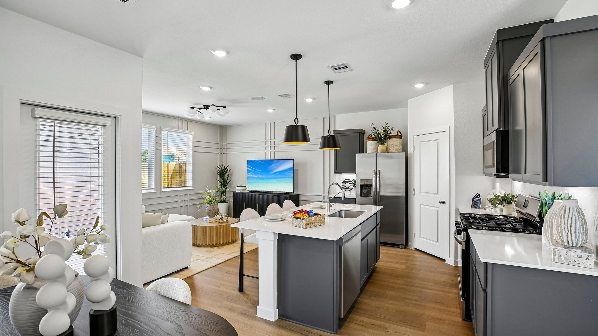 Bright kitchen showcasing quartz countertops, contemporary cabinetry, and seamless flow into the living area.