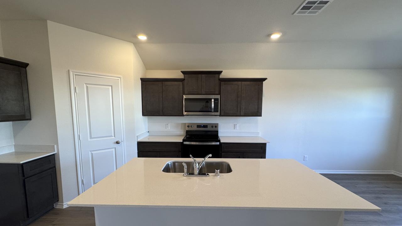Kitchen area with white counters hardwood floors and dark cabinets