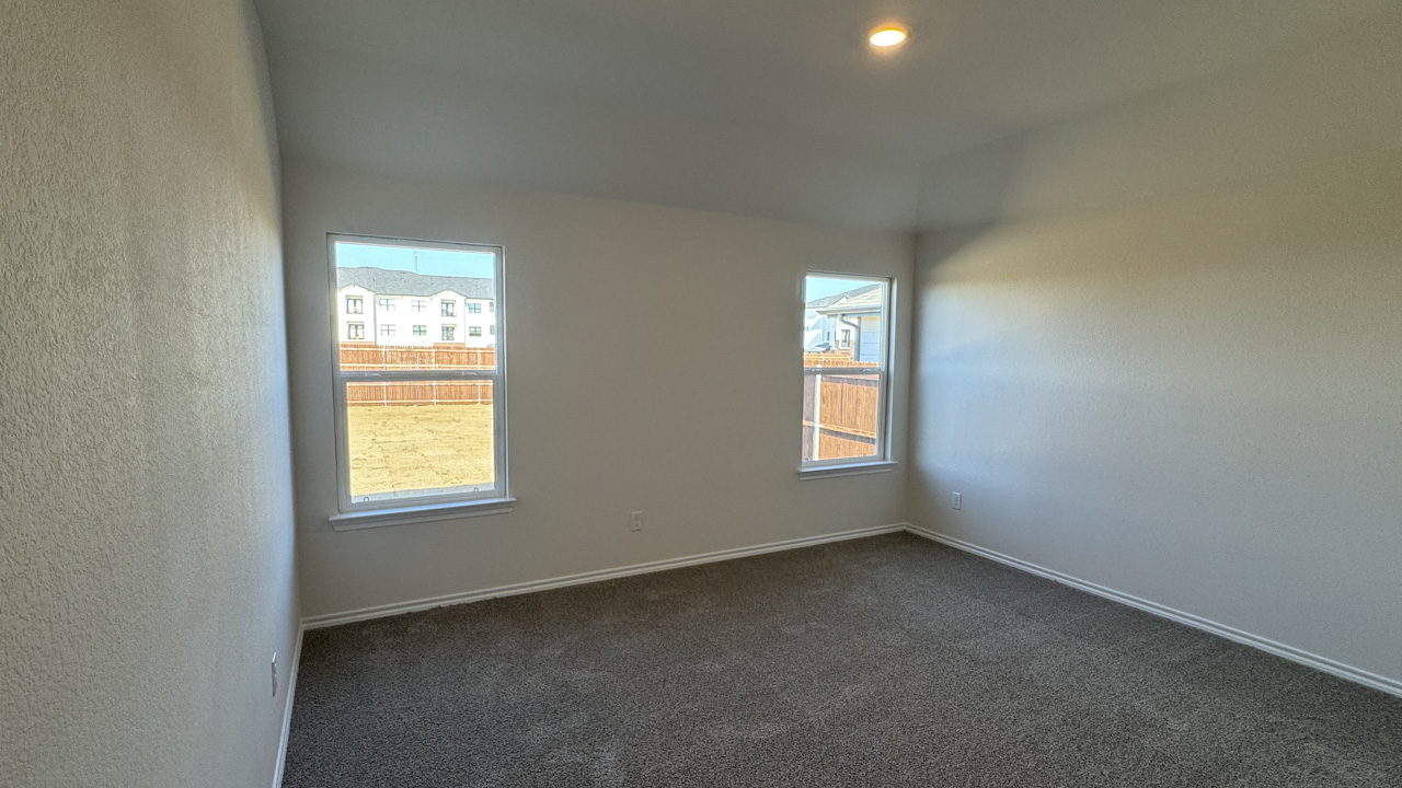 Primary bedroom with carpet and large windows facing the backyard providing natural light