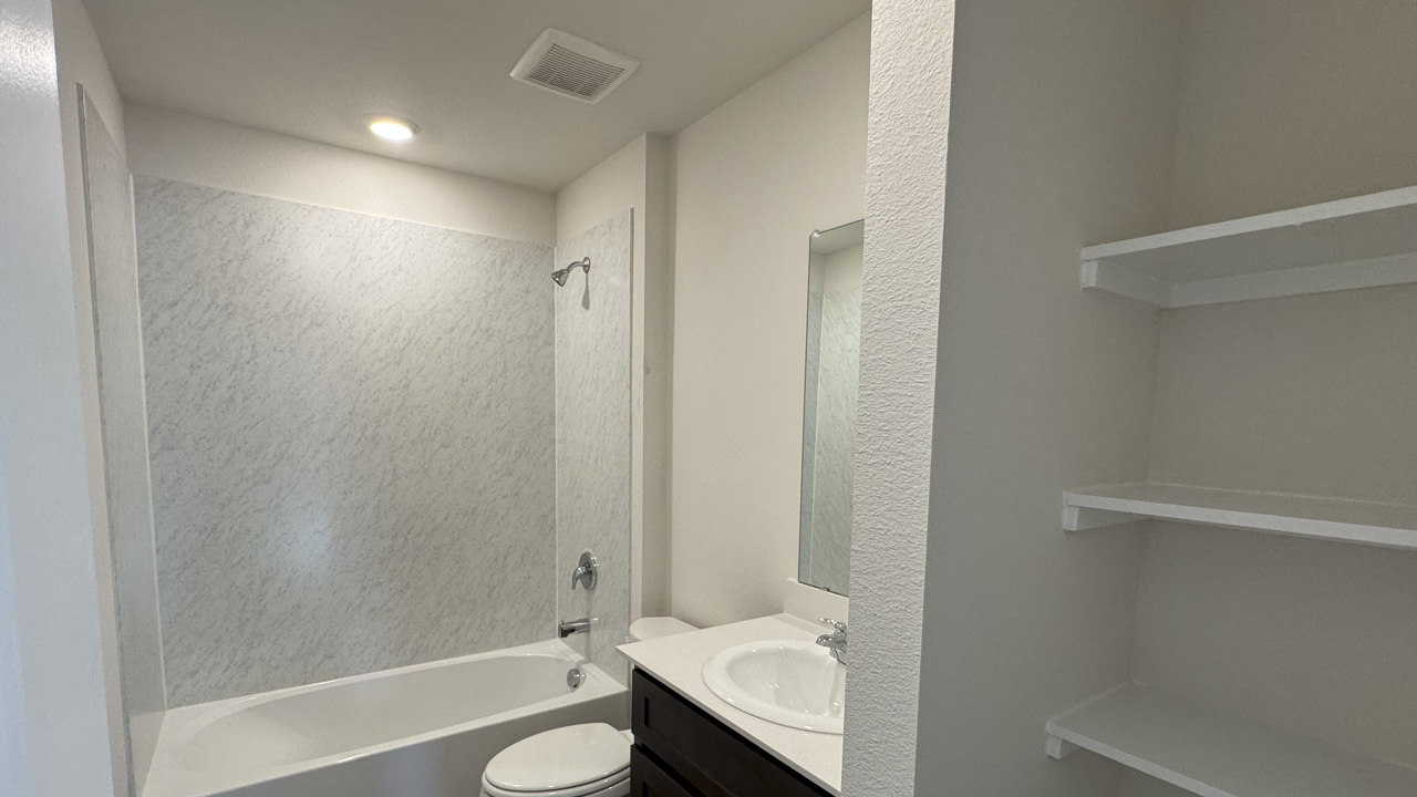 Secondary bathroom with hardwood floors dark cabinets and white counters and tub