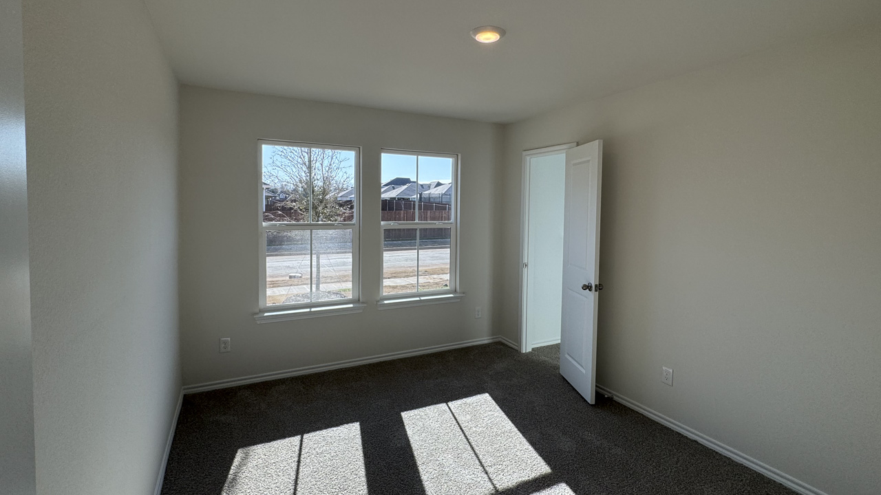 Secondary bedroom with carpet and large windows providing natural light
