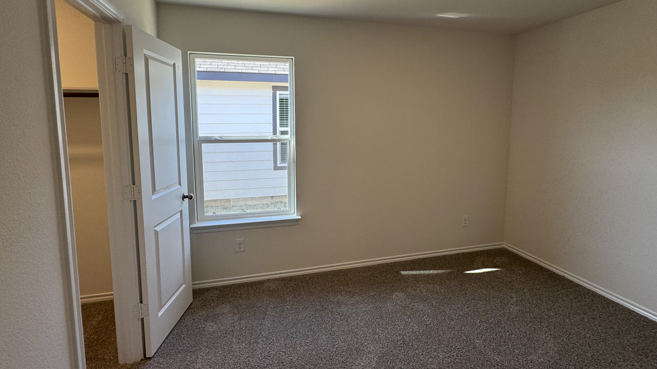 Secondary bedroom with carpet and large windows providing natural light