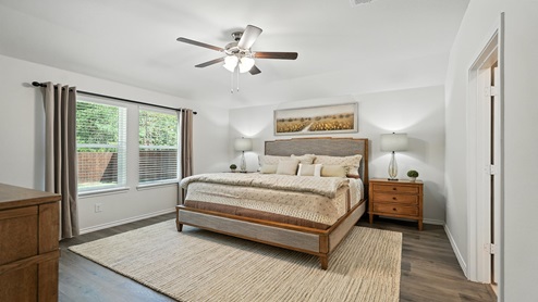 Bedroom with a large window and brown flooring.