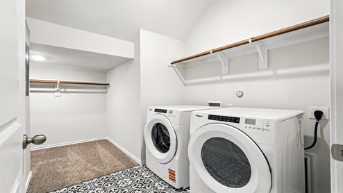 Laundry room with built in shelving and connected to a closet.