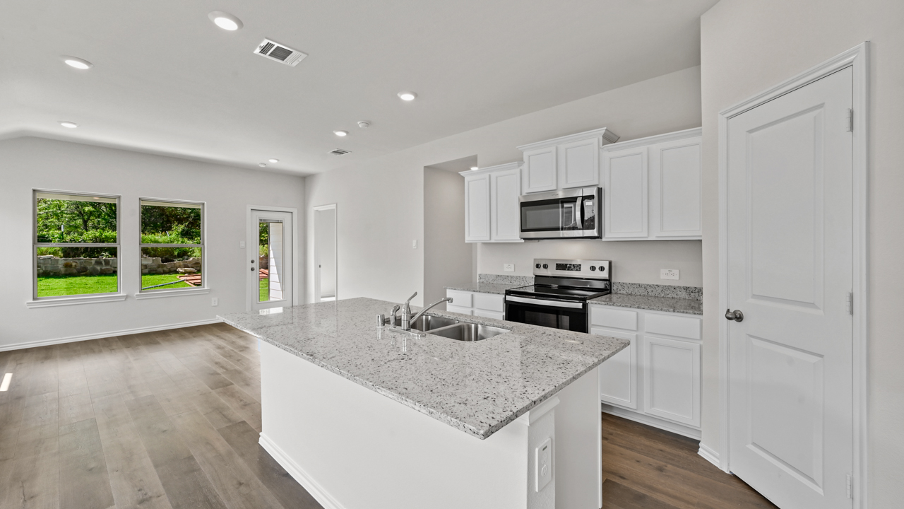 open concept kitchen with island and white cabinets overlooking breakfast nook