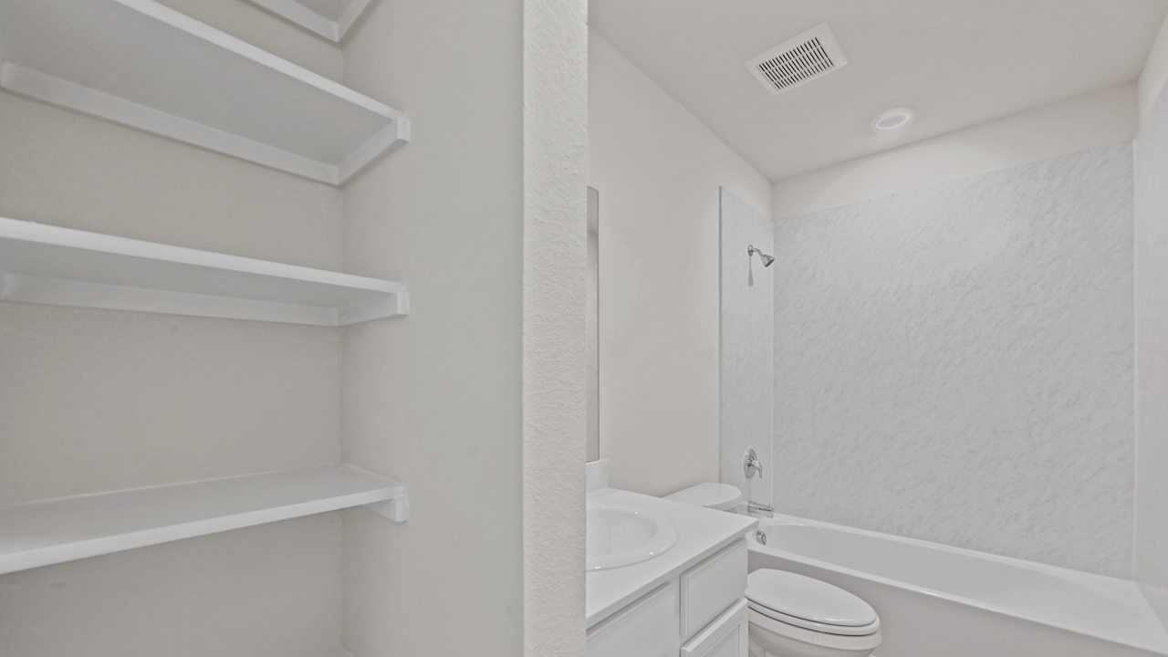 secondary bathroom with shower and storage shelves