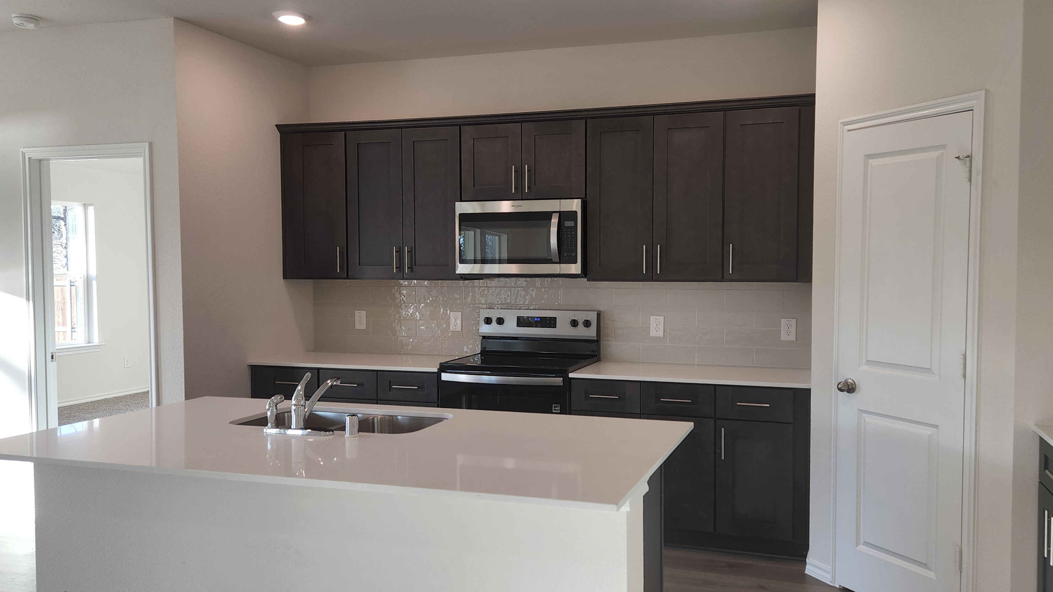 kitchen area with white counters and dark cabinets